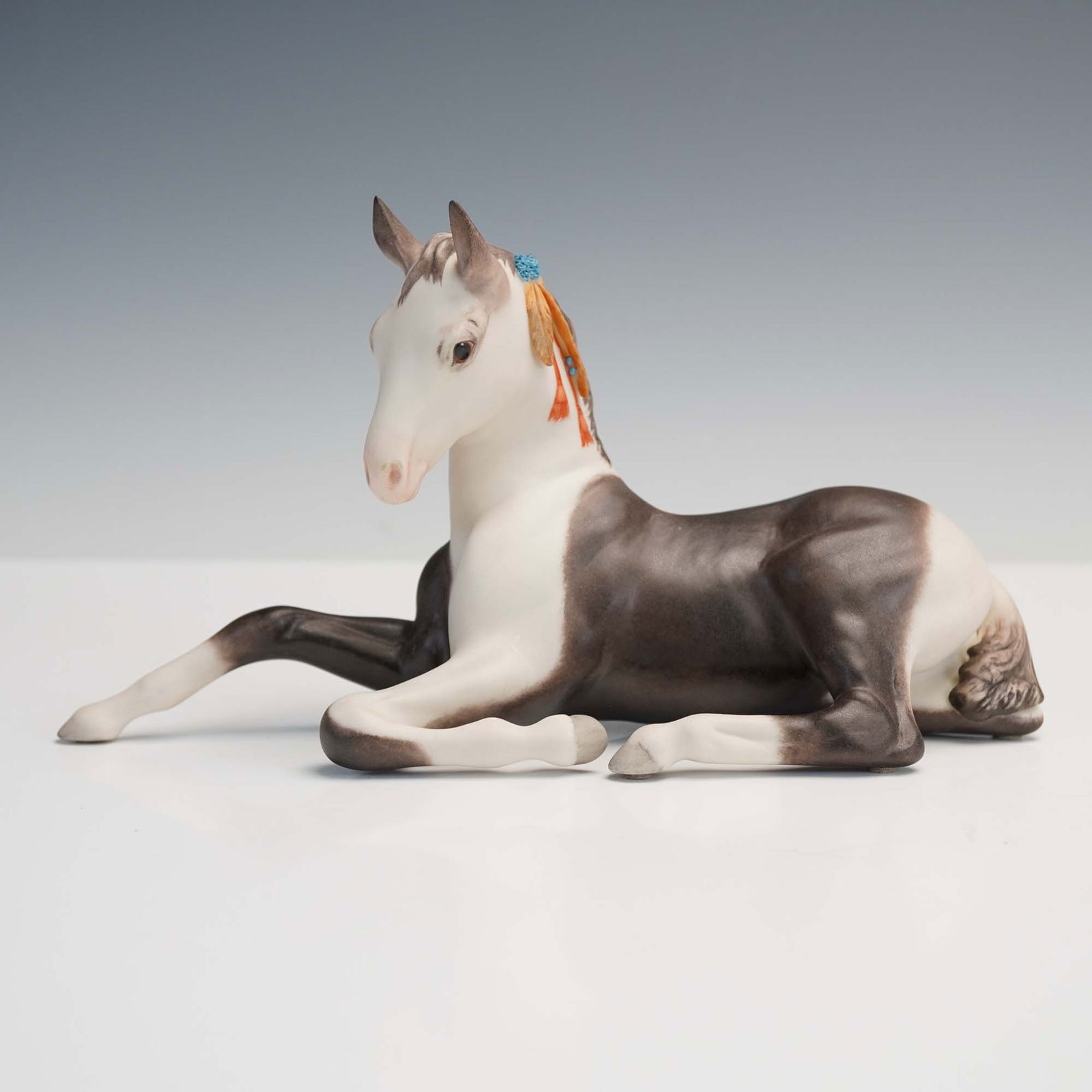 Cybis Porcelain Figurine, Pinto Colt: Crafted by the renowned American porcelain studio Cybis, this charming figurine known as the Pinto Colt captures a young foal in a relaxed, reclining pose with lifelike detailing and a soft brown-and-