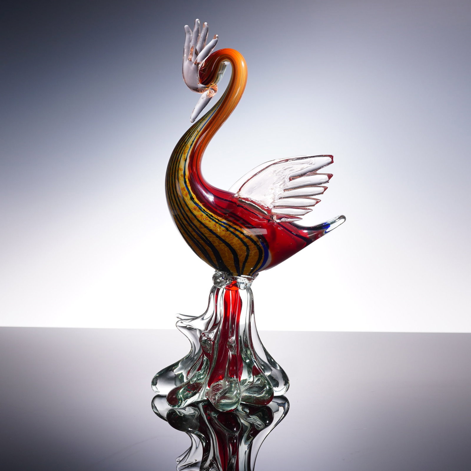 Murano Style Art Glass Figurine, Multicolor Phoenix Bird: This vivid Murano-style art glass figurine captures the elegance and flamboyance of a phoenix or exotic bird in flight, rising on a rippling clear glass base. The sweeping neck, flared wings, and outs