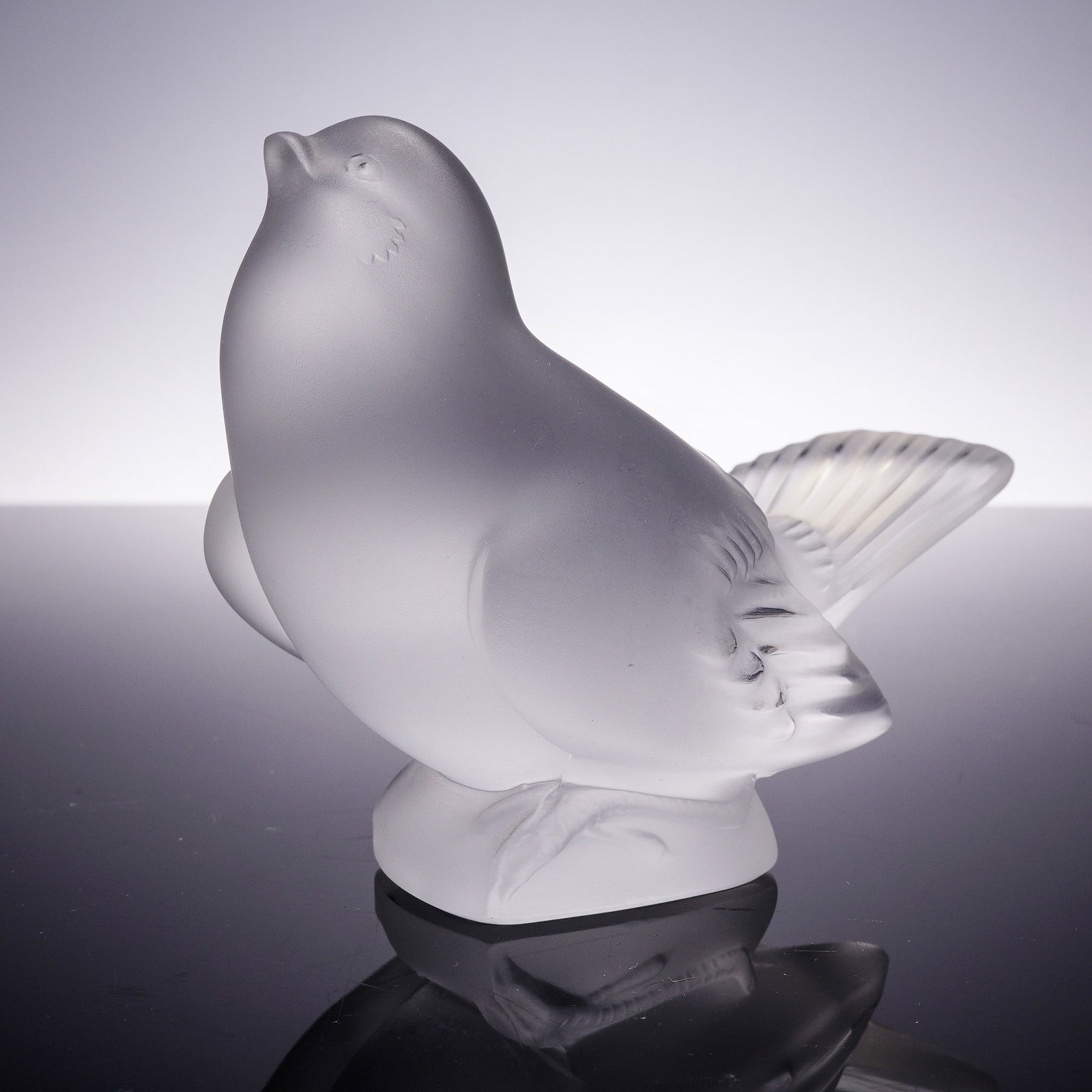 Lalique Crystal Figurine, Sparrow Head Up: This endearing frosted crystal figurine by Lalique features a sparrow perched with its head tilted upward in a lifelike, inquisitive pose. With softly rounded contours and delicate feather detailing, 
