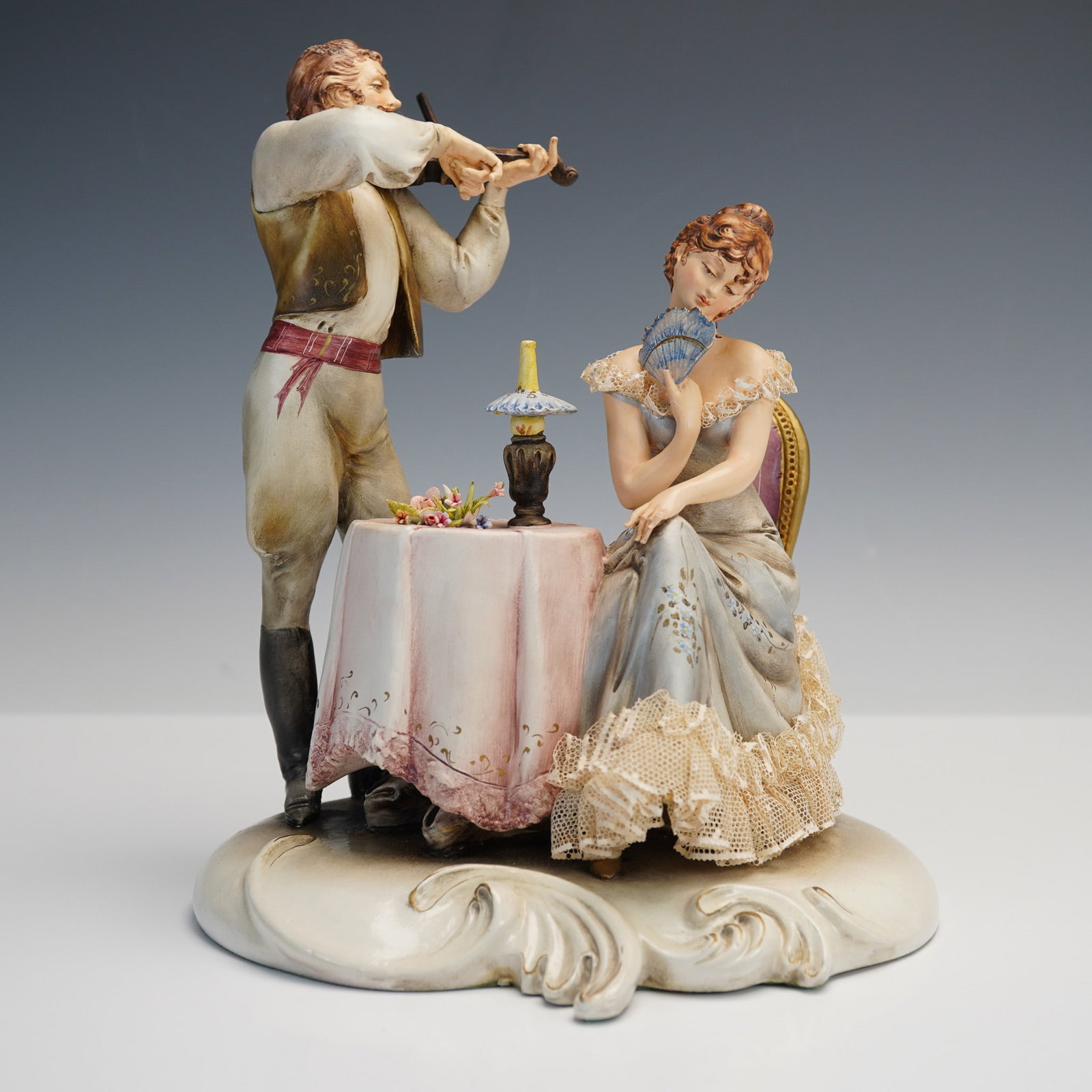 A. Borsato Porcelain Figurine, Romantic Serenade Couple: This romantic porcelain figurine by Antonio Borsato captures an enchanting scene of courtship, with a young man serenading a seated woman with his violin as she listens coyly behind a blue fan. The fi