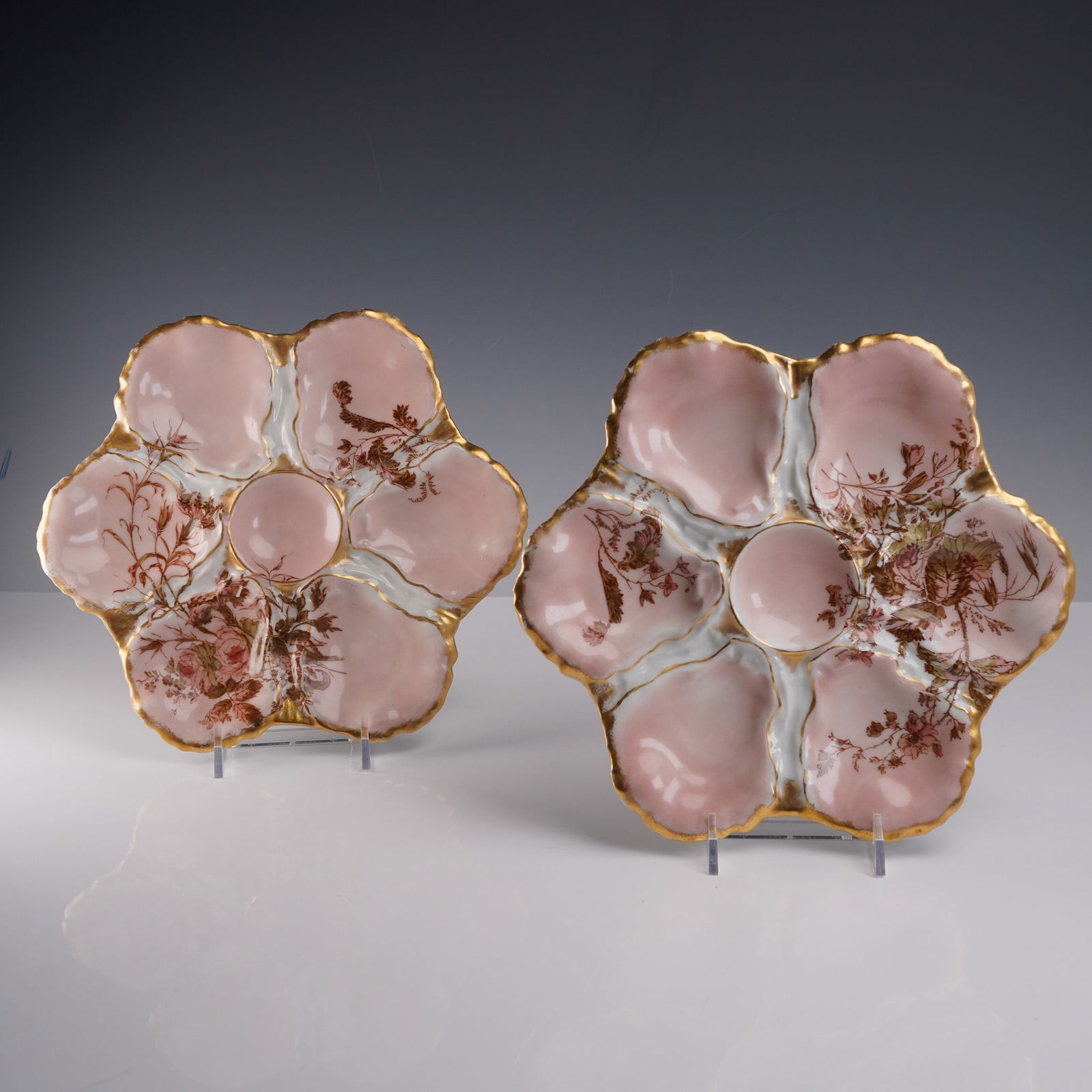 2pc Haviland & Co. Limoges Pink & Gold Oyster Plates: A refined pair of antique French porcelain oyster plates by Haviland & Co., Limoges, each crafted in a delicate six-lobed floral form with soft pink wells, a central sauce roundel, and intricate hand-