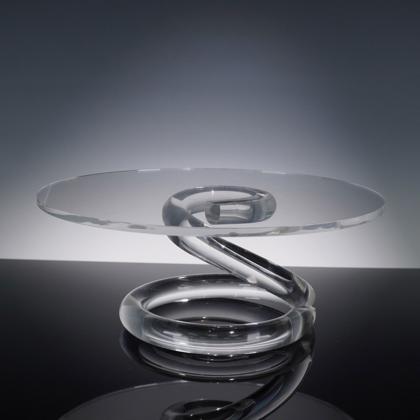 Dorothy Thorpe Lucite Cake Stand, Spiral Base: A striking mid-century modern Lucite cake stand attributed to Dorothy Thorpe, renowned for her iconic acrylic and glass designs. This piece features a sleek, clear circular top supported by a dramatic