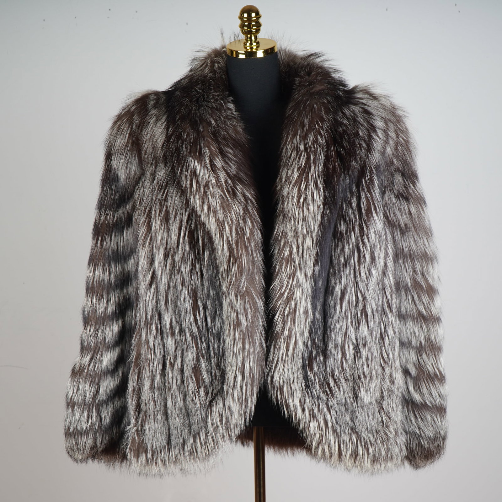 Saga Fox Fur Coat: A voluminous and exquisitely constructed fox fur coat with nylon and Bemberg lining. The coat showcases the characteristic high-contrast banding of silver fox, with tones ranging from deep charcoal to