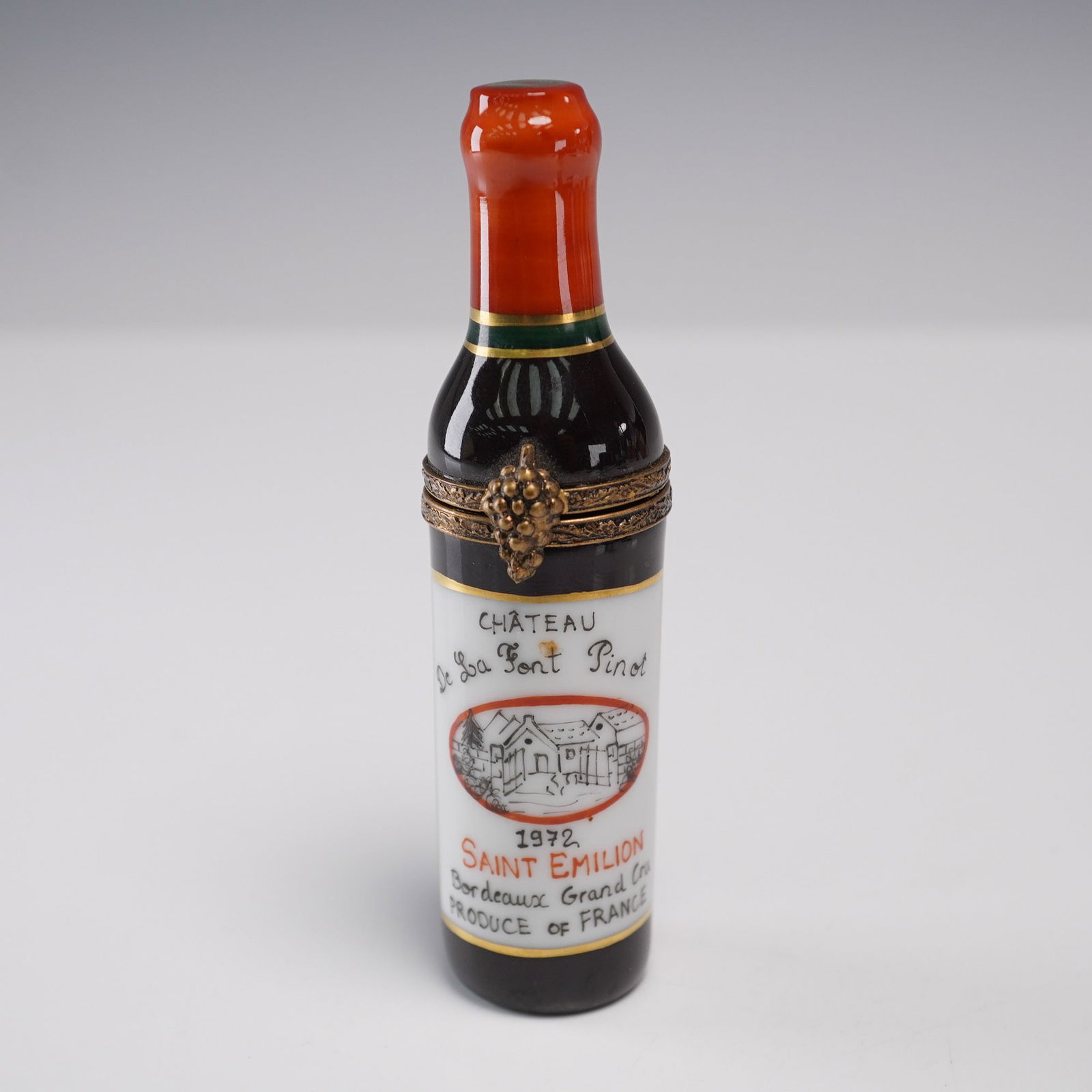 Limoges Saint-Emilion Wine Bottle Trinket Box: Hand-painted Limoges porcelain trinket box in the form of a wine bottle labeled 1972 Saint Emilion Bordeaux Grand Cru. Marked Peint main Limoges France inside and adorned with a gilt grape-cluster cla