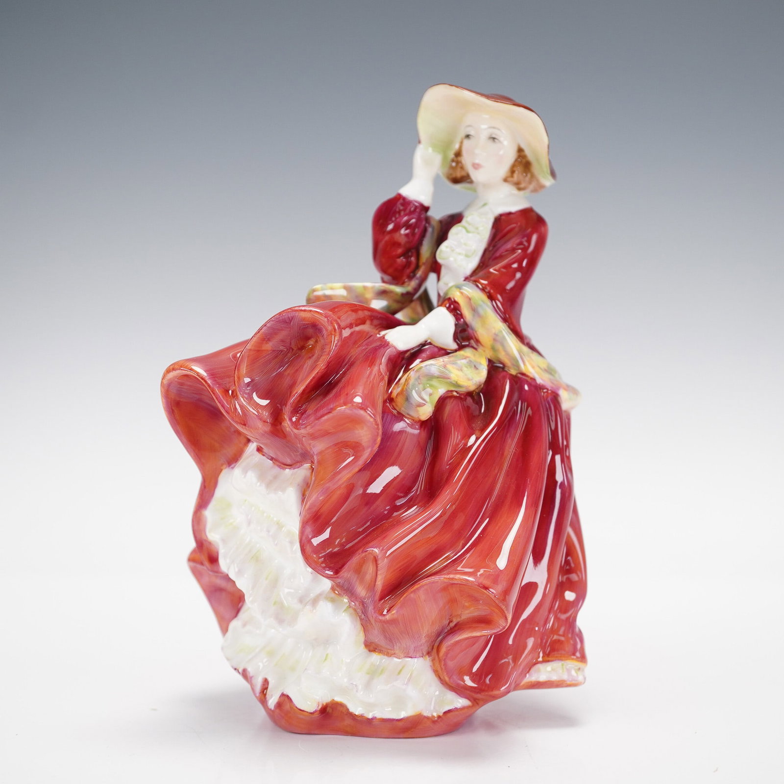 Royal Doulton Figurine, Top O' The Hill HN1937: Modeled in a beautiful red dress with a colorful scarf. Royal Doulton backstamp. Artist: Leslie Harradine Issued: 1937 - 2004 Dimensions: 4.25"L x 4.5"W x 7"H Country of Origin: England