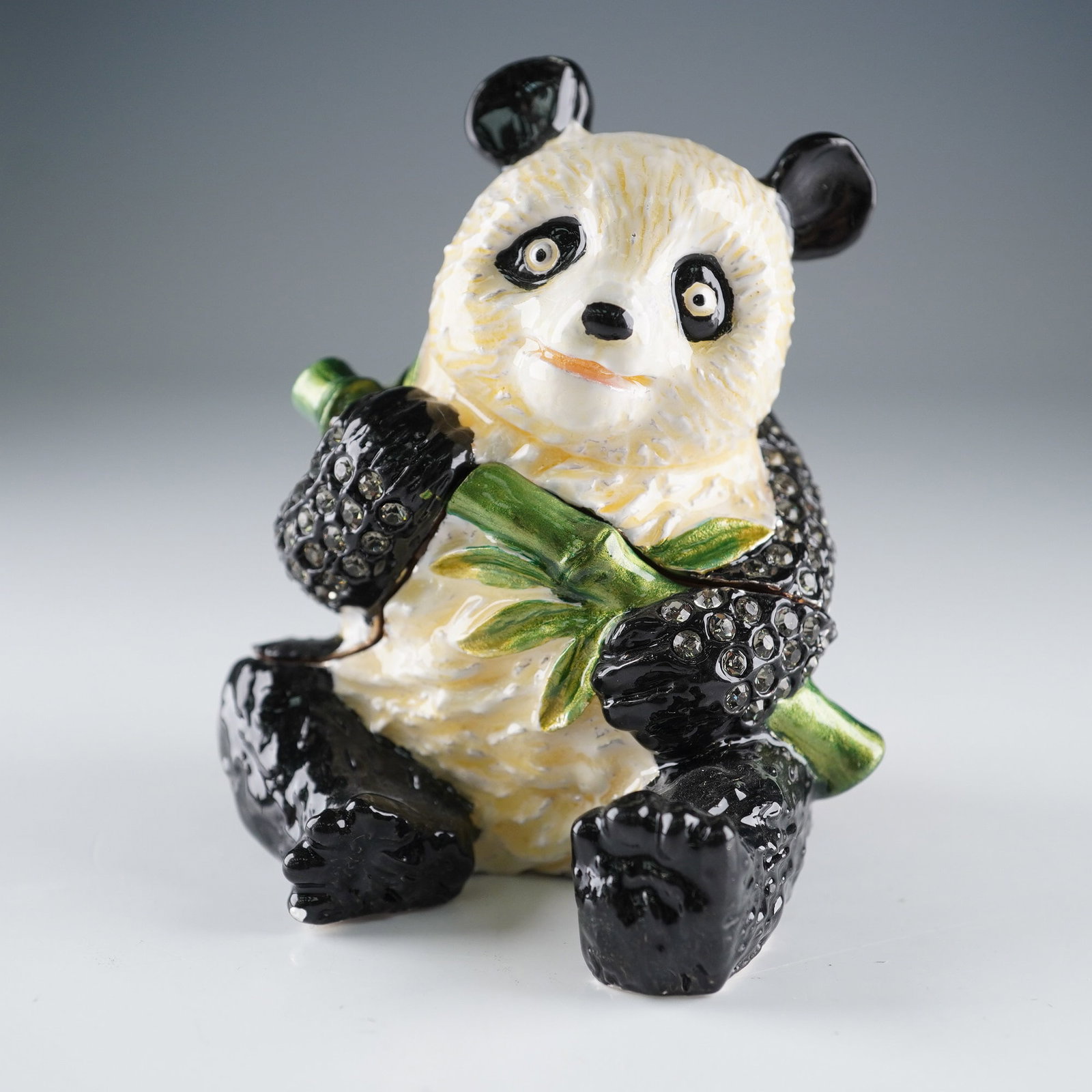 Rucinni Jeweled Panda Trinket Box: Rucinni delightful trinket box featuring a seated panda clutching a bamboo stalk. The hinged design opens at the midsection to reveal a smooth, cream-toned enamel interior with magnetic closure. Inter