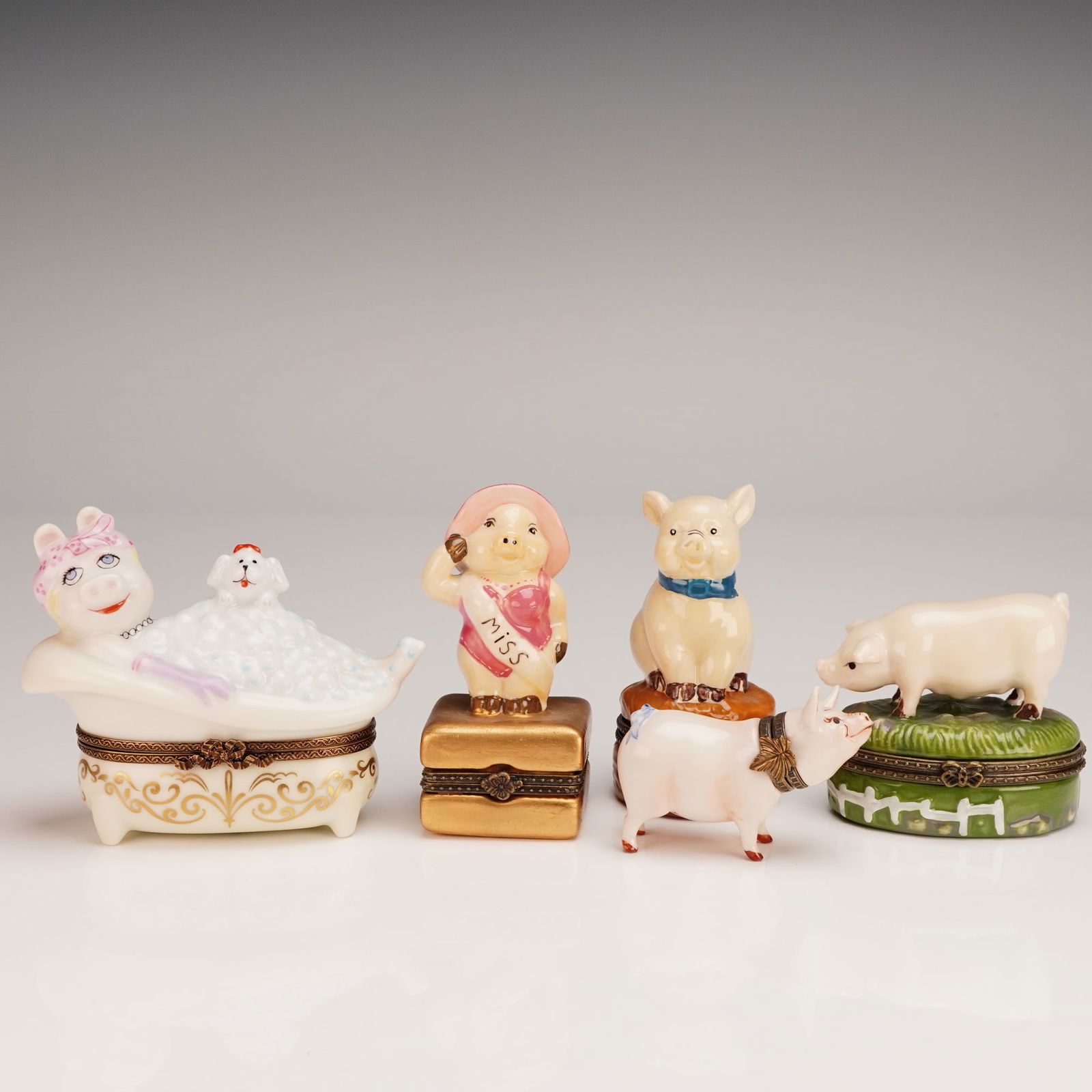 5pc Limoges Pig-Themed Porcelain Treasure Boxes: Charming set of five hand-painted porcelain pig-themed treasure boxes, each with hinged lids and whimsical character designs, including a Bernardaud Limoges France "Dans le Bain" box depicting a pig i