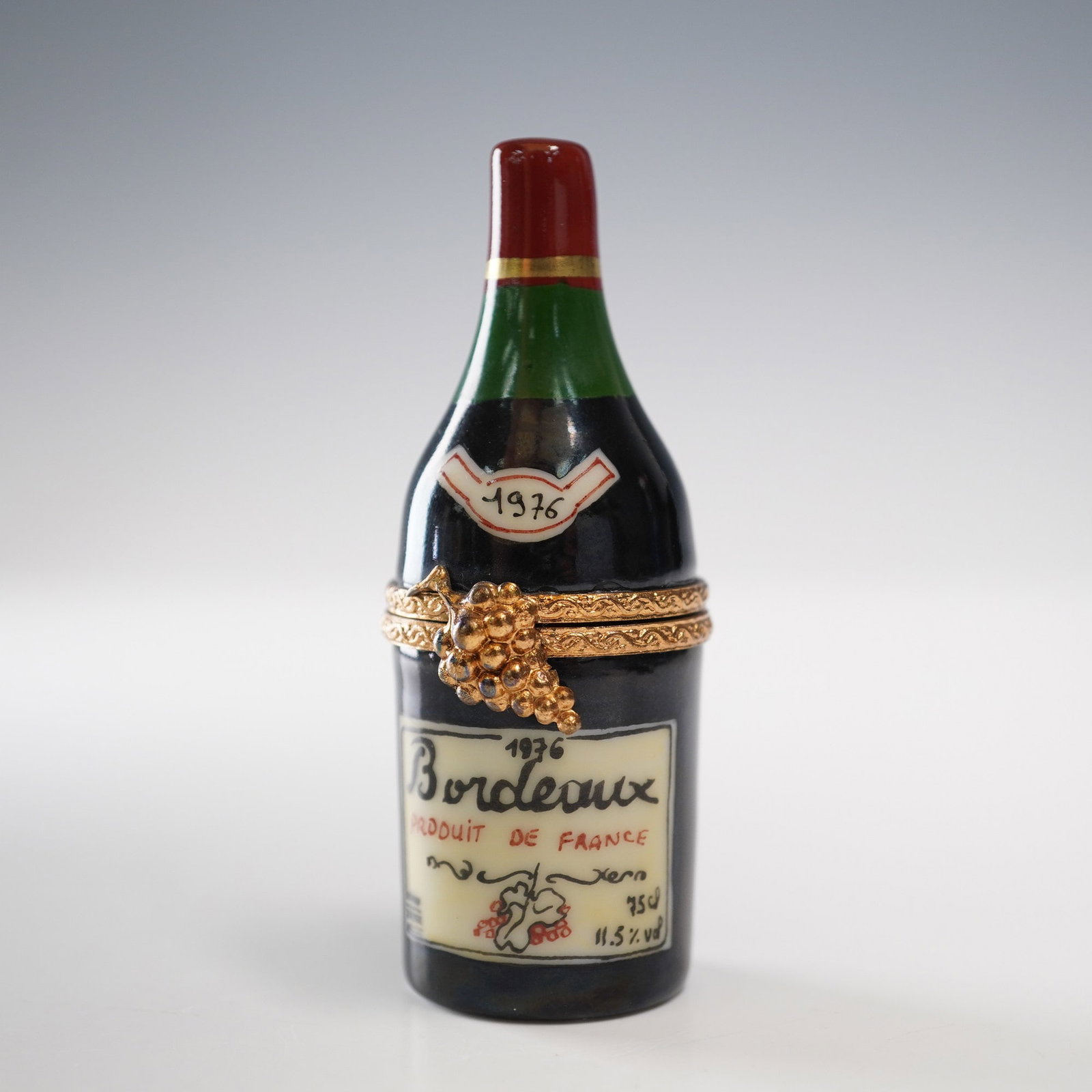2pc Limoges Porcelain Bordeaux Wine Bottle Trinket Box With Bottle Figurine: Hand-painted Limoges porcelain trinket box in the form of a 1976 Bordeaux wine bottle, complete with vintage-style labeling and a green-glazed neck. The hinged top opens to reveal a miniature porcelai