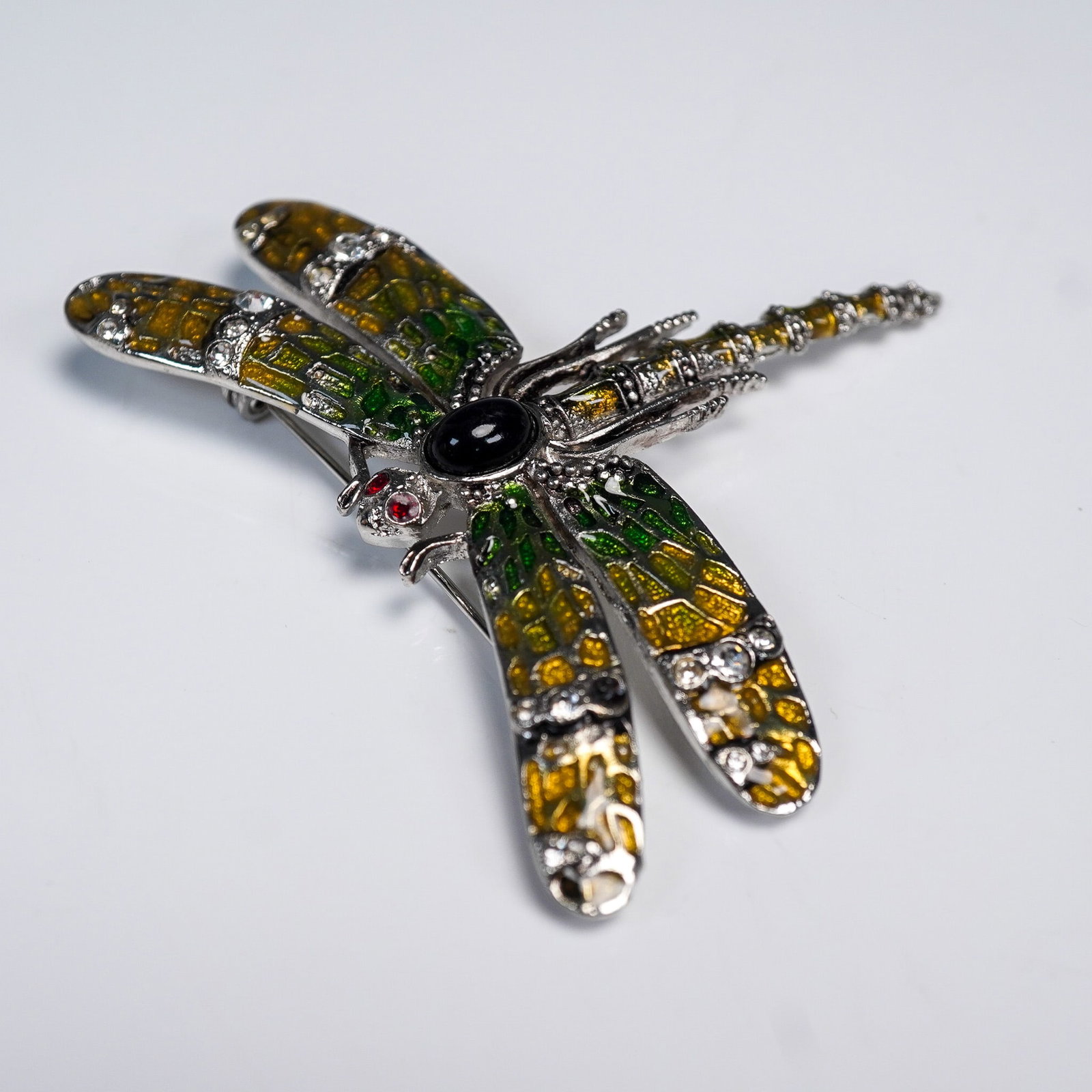 Landau Enamel Dragonfly Brooch with Rhinestones: Silver tone dragonfly brooch by Landau featuring vibrant enamel wings in shades of green and yellow, accented with clear rhinestones. The body includes a central black cabochon and two small red rhine