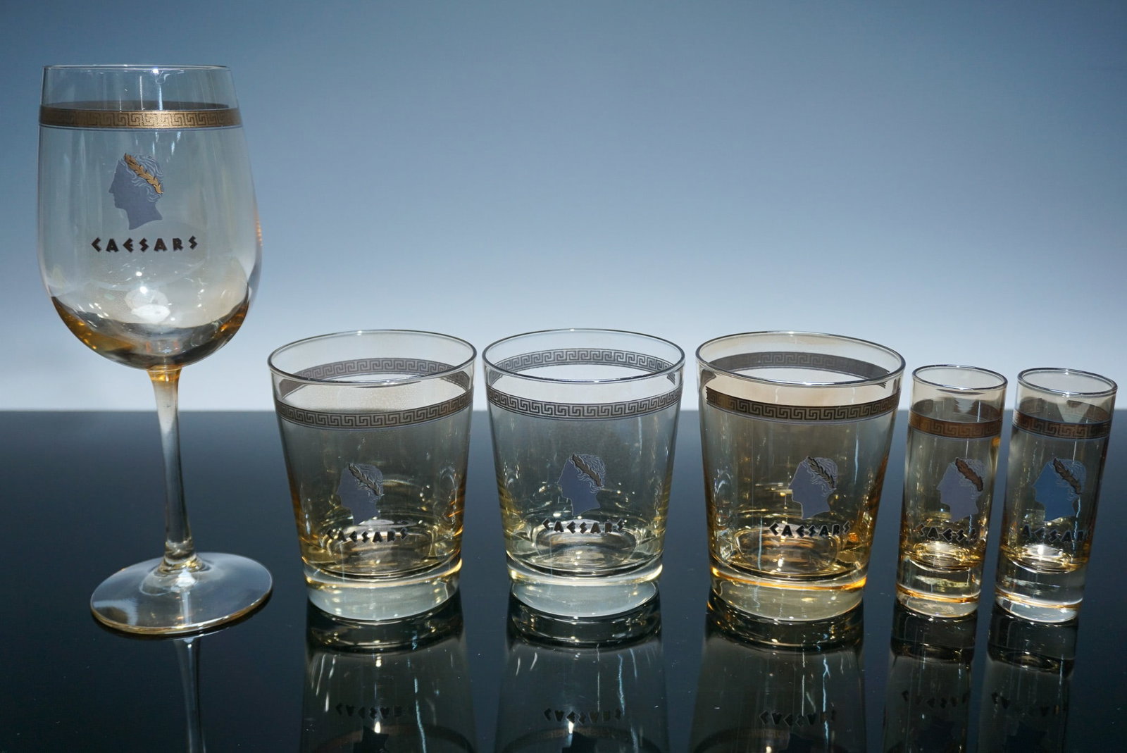 6pc Caesars Etched Glassware Set with Gold Trim: Six-piece Caesars Palace glassware set featuring gold Greek key trim and etched silhouette profiles with laurels. Includes one 9.25"H wine glass, three 4"H rocks glasses, and two 4.25"H shot glasses. 