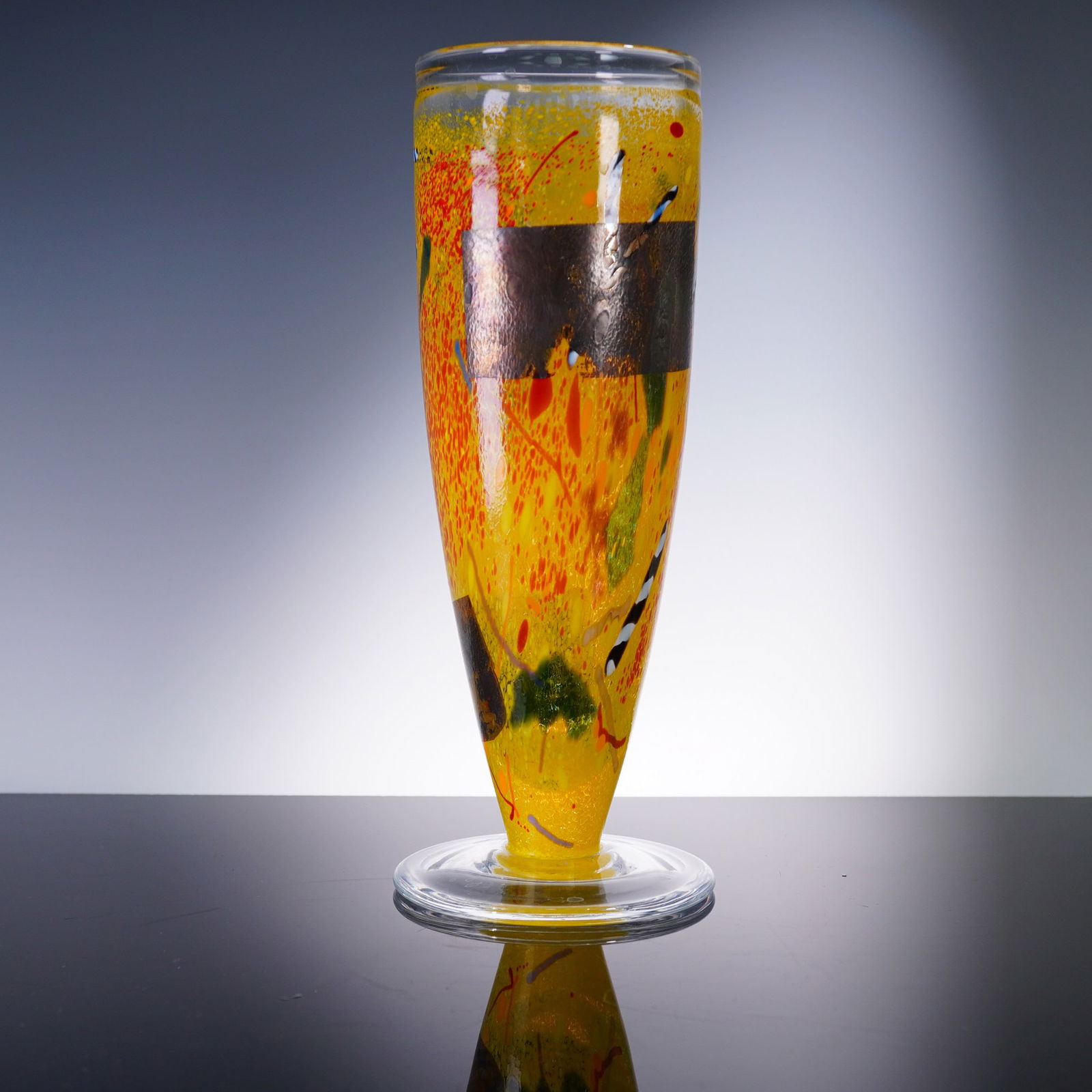 Kosta Boda Art Glass Vase by Bertil Vallien: Designed by renowned Swedish artist Bertil Vallien for Kosta Boda, this vibrant art glass vase showcases a bold abstract composition in vivid yellow, orange, green, and black tones, accented with meta