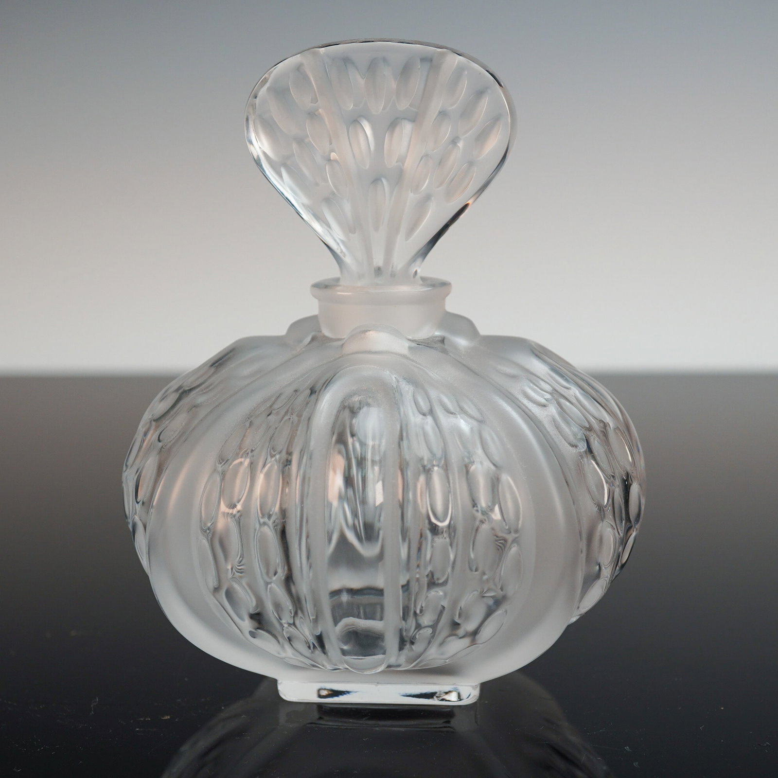 Lalique France Frosted Crystal Bottle: Finely crafted Lalique France crystal bottle featuring frosted and clear motifs with rounded lobes and a broad leaf-form stopper. This sculptural vessel showcases Lalique's signature satin-finished gl