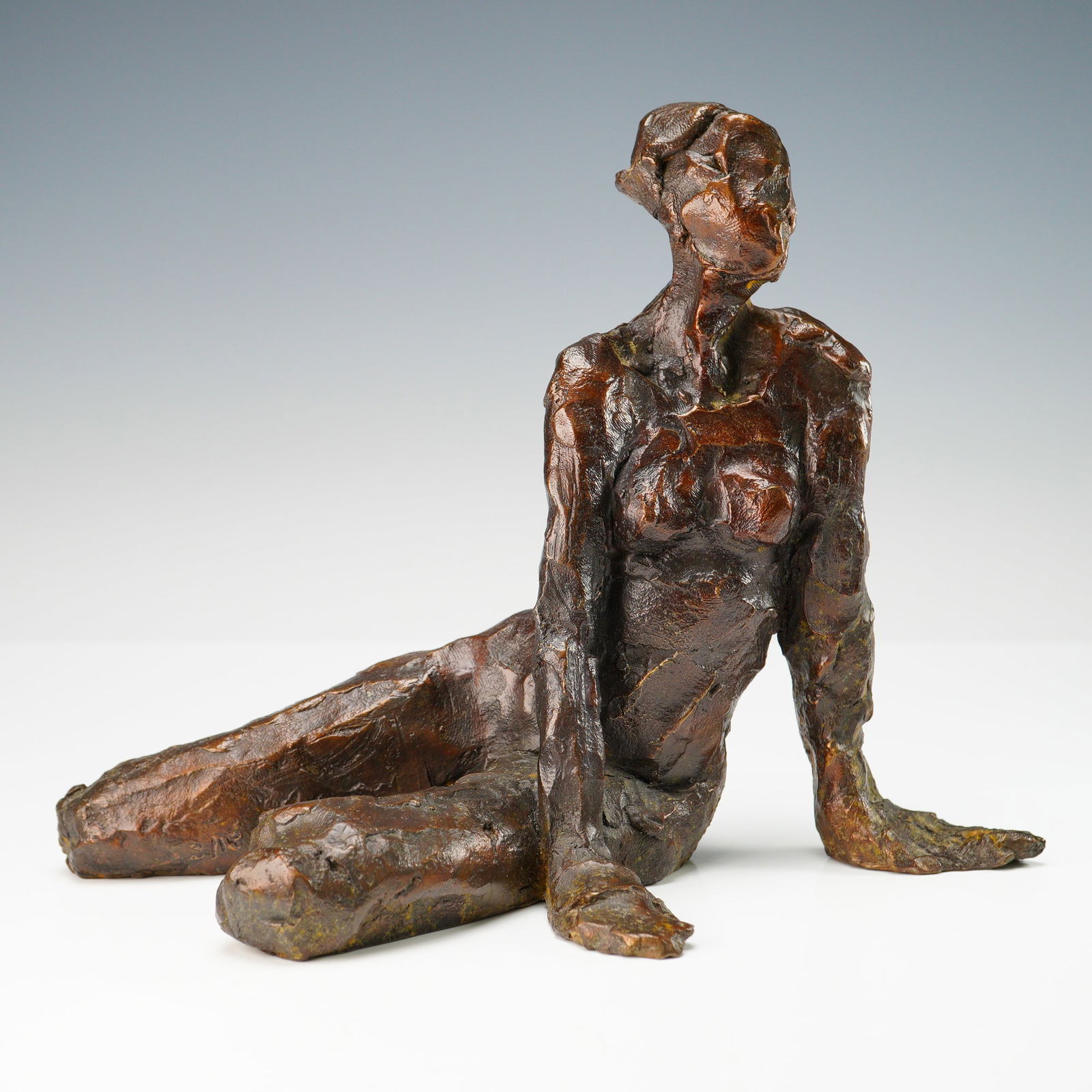 Curt Brill Bronze Figurative Sculpture, Upright Nude 1996: This bronze sculpture by Curt Brill presents a seated female nude with an upright, poised torso and inward gaze. The figure's grounded posture and extended legs evoke a moment of meditative calm, rend