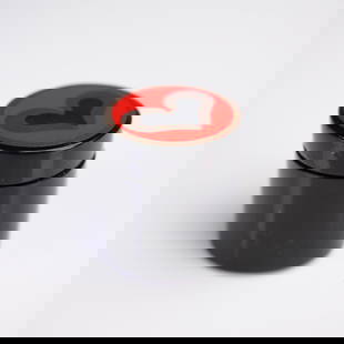 Heart Motif Jewelry Box: A small cylindrical lacquered box with a glossy black finish. The lid features a bold circular panel decorated with a stylized heart design in red, black and metallic bronze tones. The interior is smo