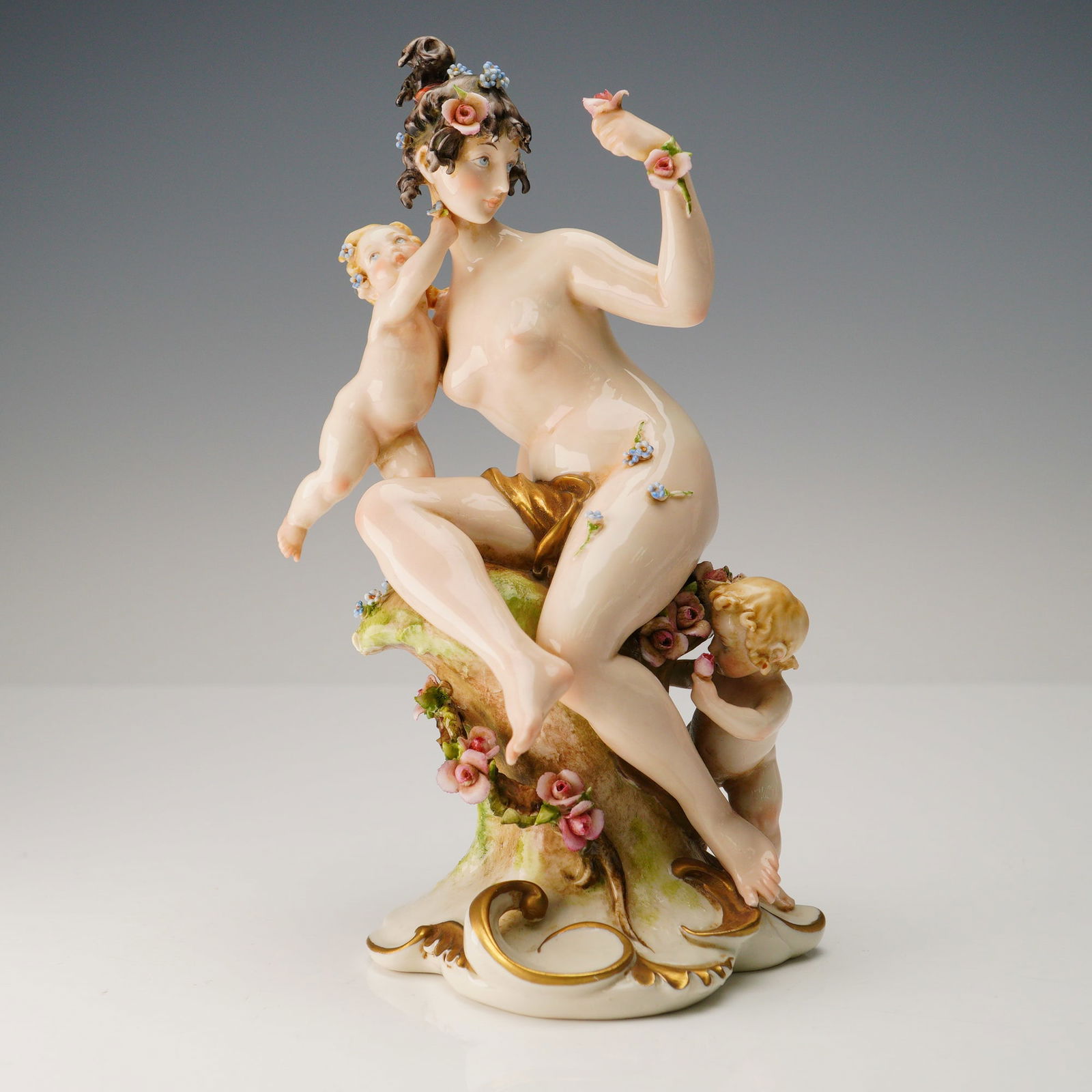 Giuseppe Cappe for Capodimonte Porcelain Nude Female with Cherubs: An exquisitely modeled Capodimonte porcelain figurine by Giuseppe Cappe, depicting a nude female figure - likely an allegorical representation of Bacchus muse or a classical goddess - seated amidst ch