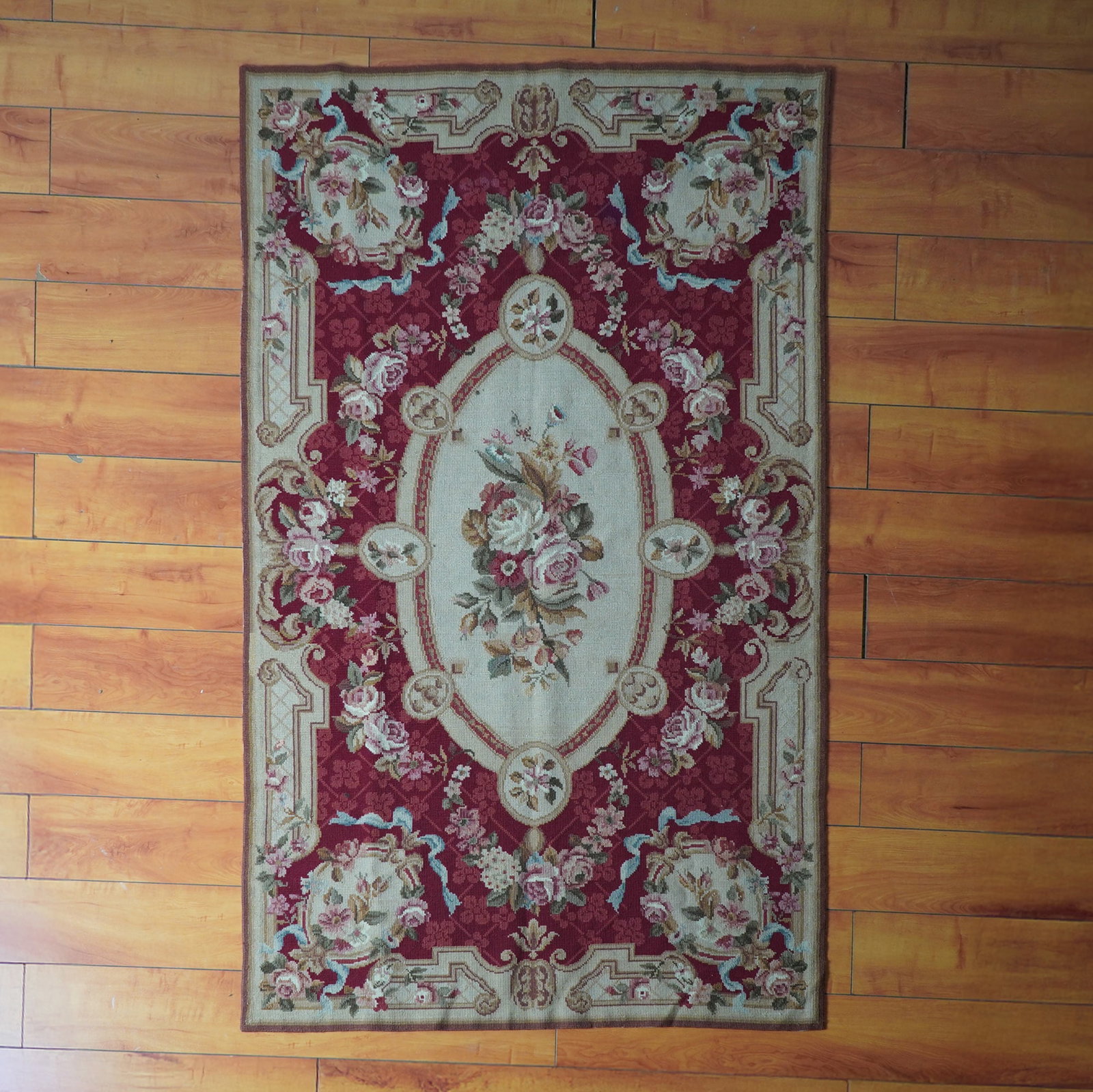 French Provincial Aubusson Hand-Woven Floral Rug: Step into timeless European charm with this stunning Aubusson style hand-woven rug, richly adorned in a deep crimson and ivory palette with a central floral medallion flanked by rose garlands, acanthu