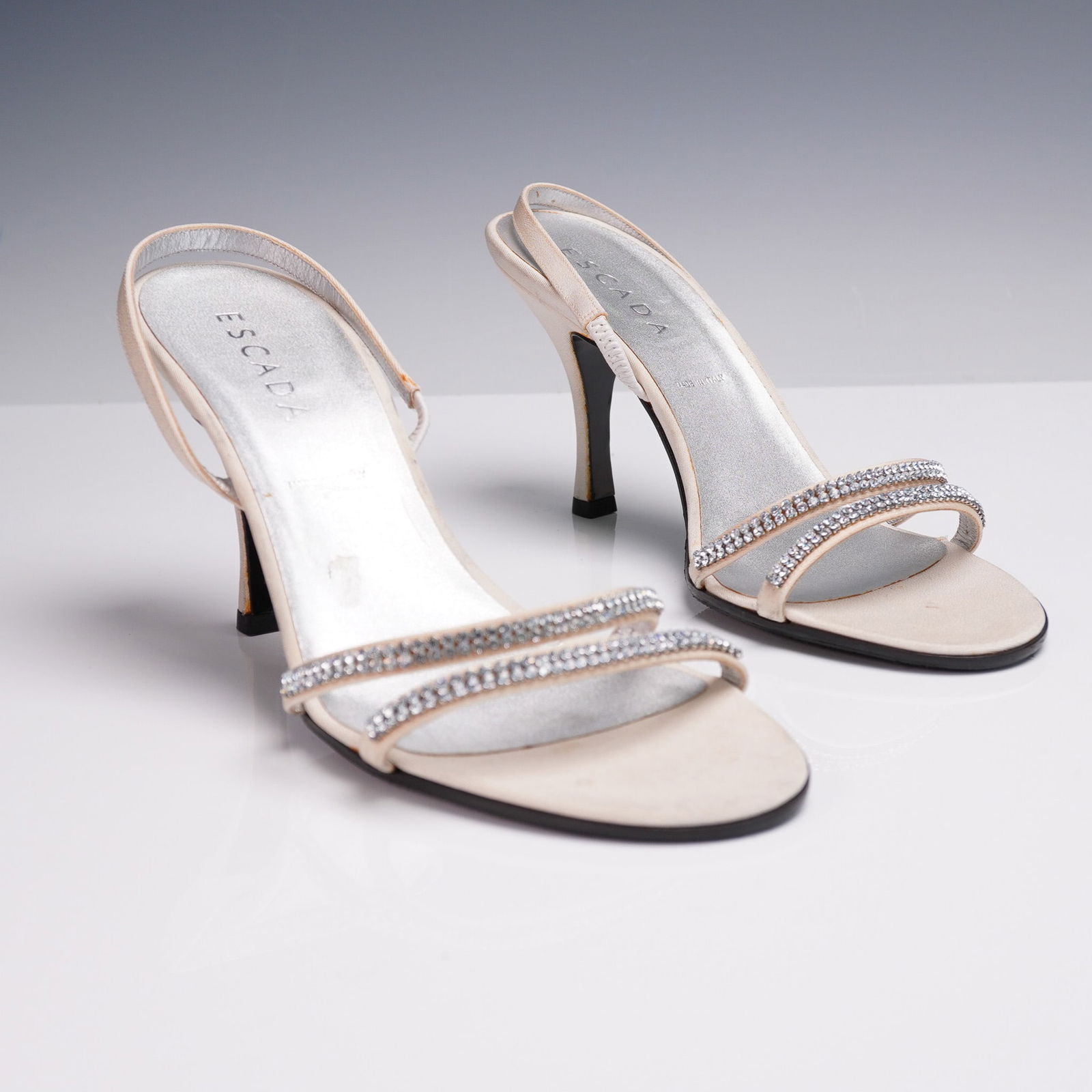 Escada Crystal Embellished Slingback Sandals: Elegant and glamorous, these Escada slingback sandals are crafted in Italy from soft champagne-hued satin and accented with twin rows of sparkling rhinestone embellishments across the front straps. Se