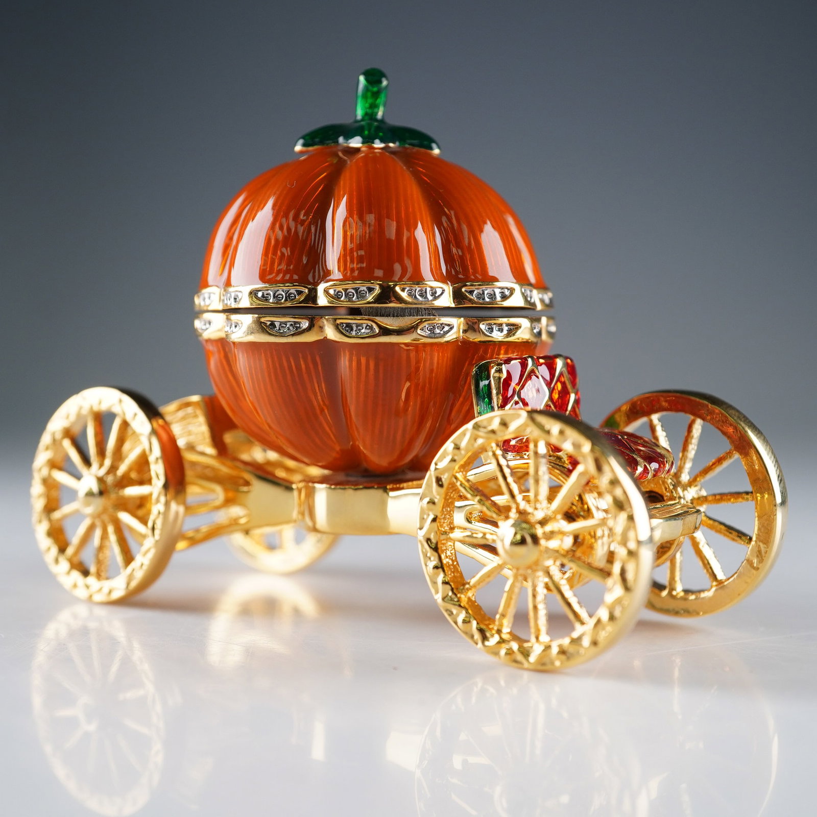 Rucinni Jeweled Pumpkin Carriage Trinket Box: Charming and fairy tale-inspired, this jeweled trinket box by Rucinni is crafted in the shape of a pumpkin carriage. Finished in glossy orange enamel with gold-tone wheels and accents, the design is e