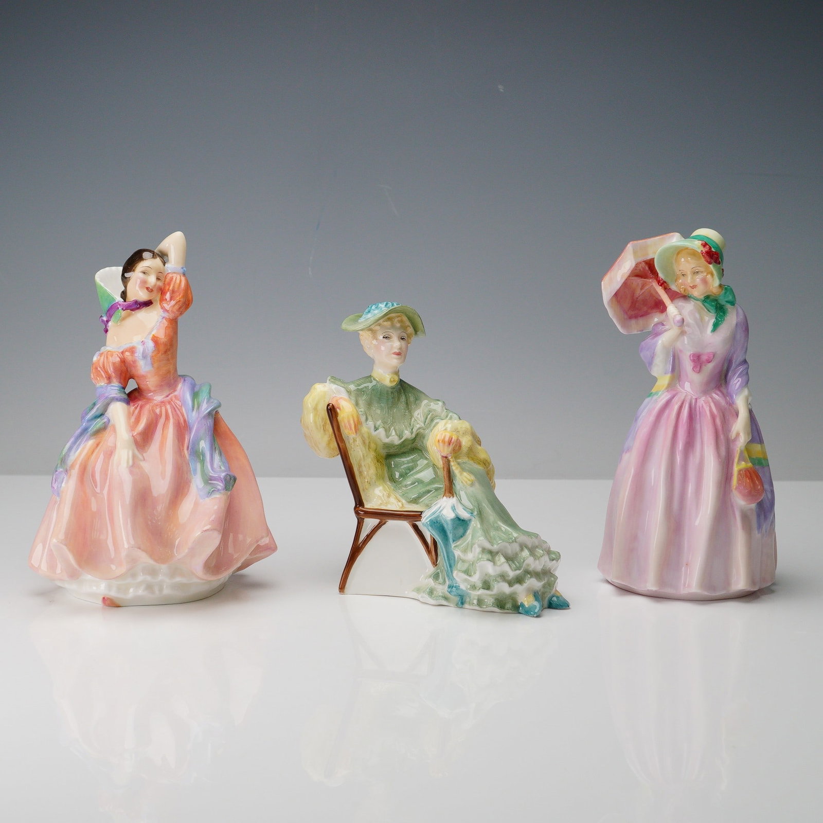 3pc Royal Doulton Porcelain Figurines, Miss Demure, Ascot, Maytime: Made in England by Royal Doulton, this trio of fine bone china figurines includes Miss Demure (HN 1402), Ascot (HN 2356), and Maytime (HN 2113), each showcasing the brand's celebrated craftsmanship an