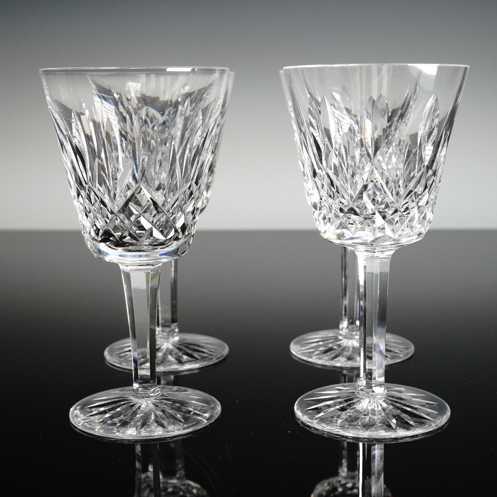 4pc Waterford Crystal Claret Wine Glasses, Lismore: These four Waterford Crystal Lismore claret wine glasses feature the iconic diamond and wedge cuts that refract light brilliantly, rising from slender faceted stems to starburst cut round bases and be