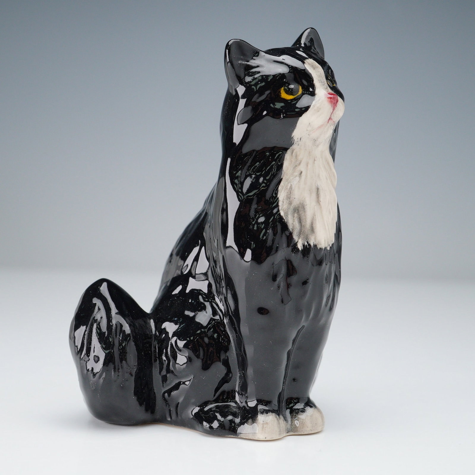 Royal Doulton Porcelain FigurineSeated Cat DA194: Features a seated cat in striking black and white coloration. Rendered in fine bone china with a glossy finish, the cat is sculpted with lifelike texture and a dignified pose, its fur flowing down int