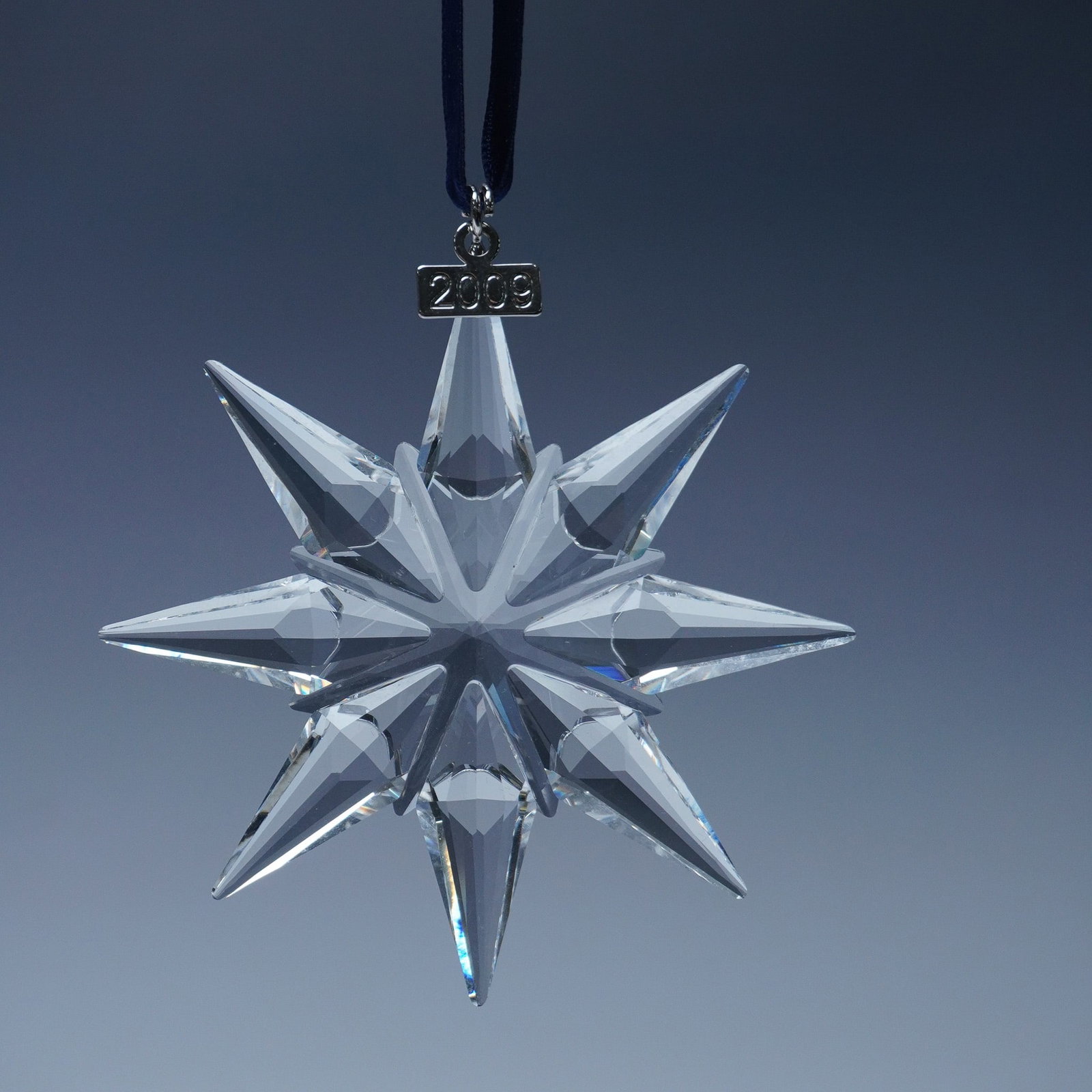Swarovski Crystal 2009 Christmas Ornament: This limited edition Swarovski crystal ornament from 2009 features an exquisite twelve-point star design, expertly cut to maximize brilliance and light reflection. The elegant symmetry of the elongate