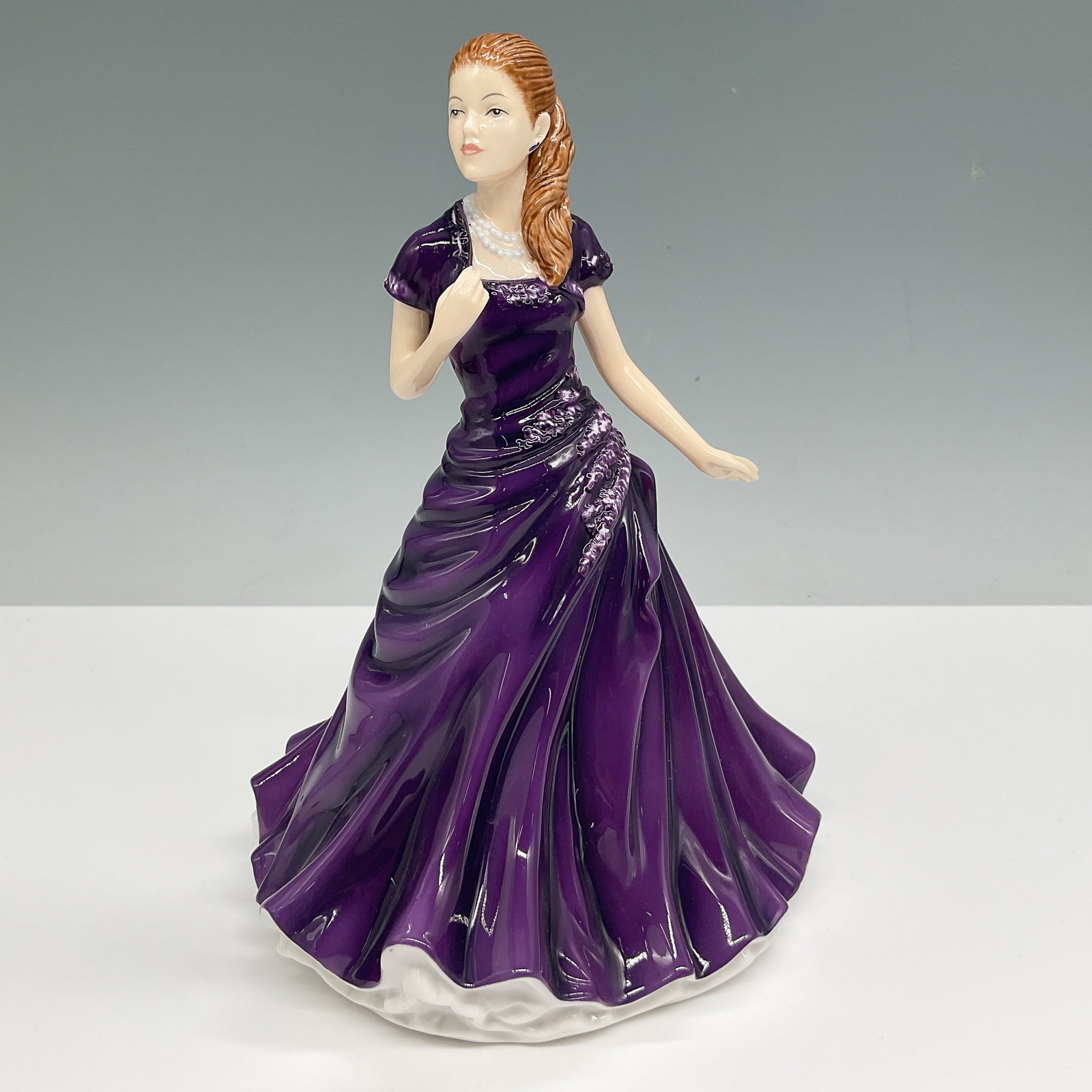 Royal Doulton Figurine Lisa HN5600: Royal Doulton figurine Lisa HN5600, a beautifully crafted porcelain piece featuring a young woman in an elegant deep purple gown with floral accents. Designed with exquisite detailing, the figurine ca