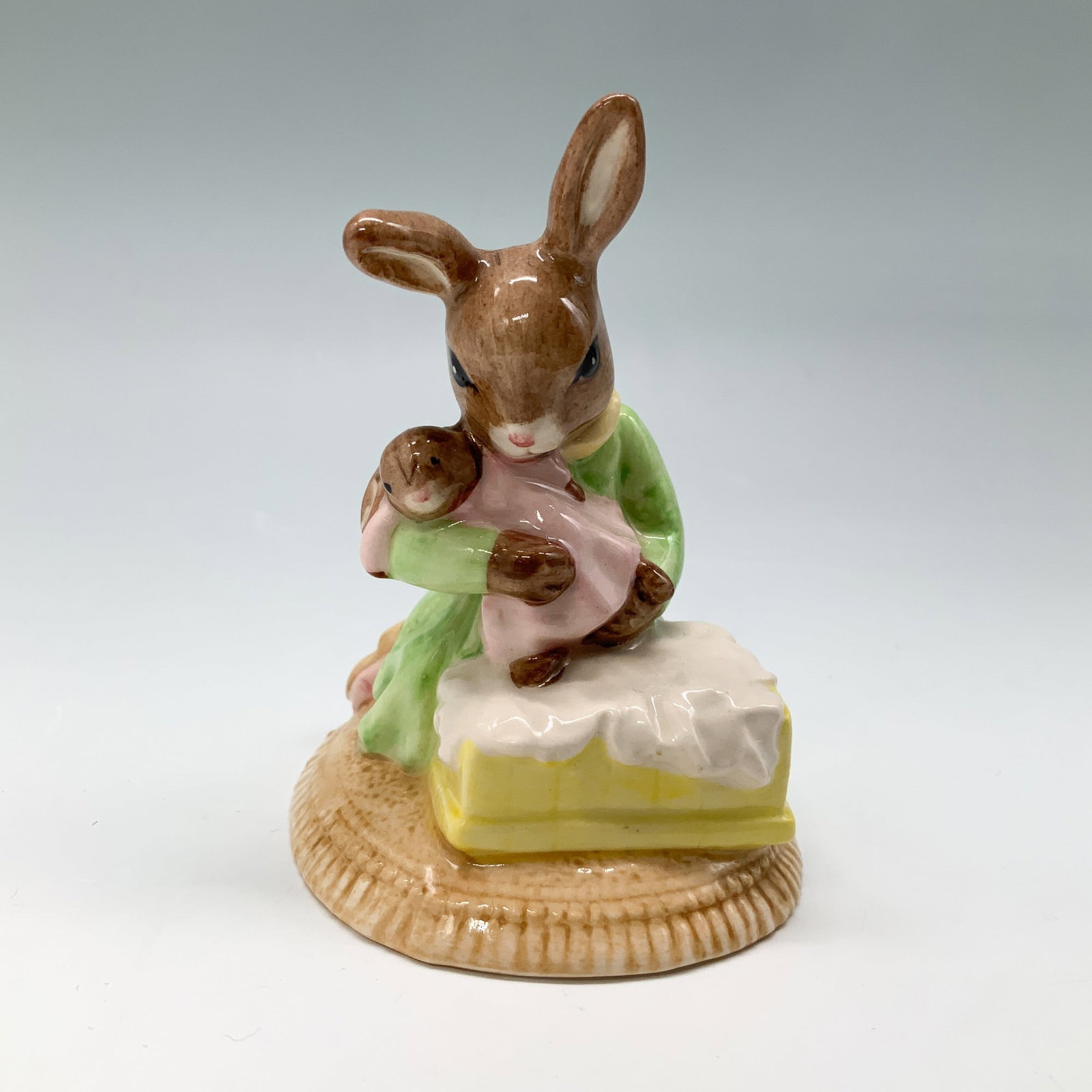 Royal Doulton Bunnykins Figurine, Sweet Dreams DB276 w/ Box: This Royal Doulton Bunnykins figurine, titled Sweet Dreams, features a mother bunny holding her baby, seated beside a cradle. Handcrafted from fine bone china, this piece is hand-painted and adorned w