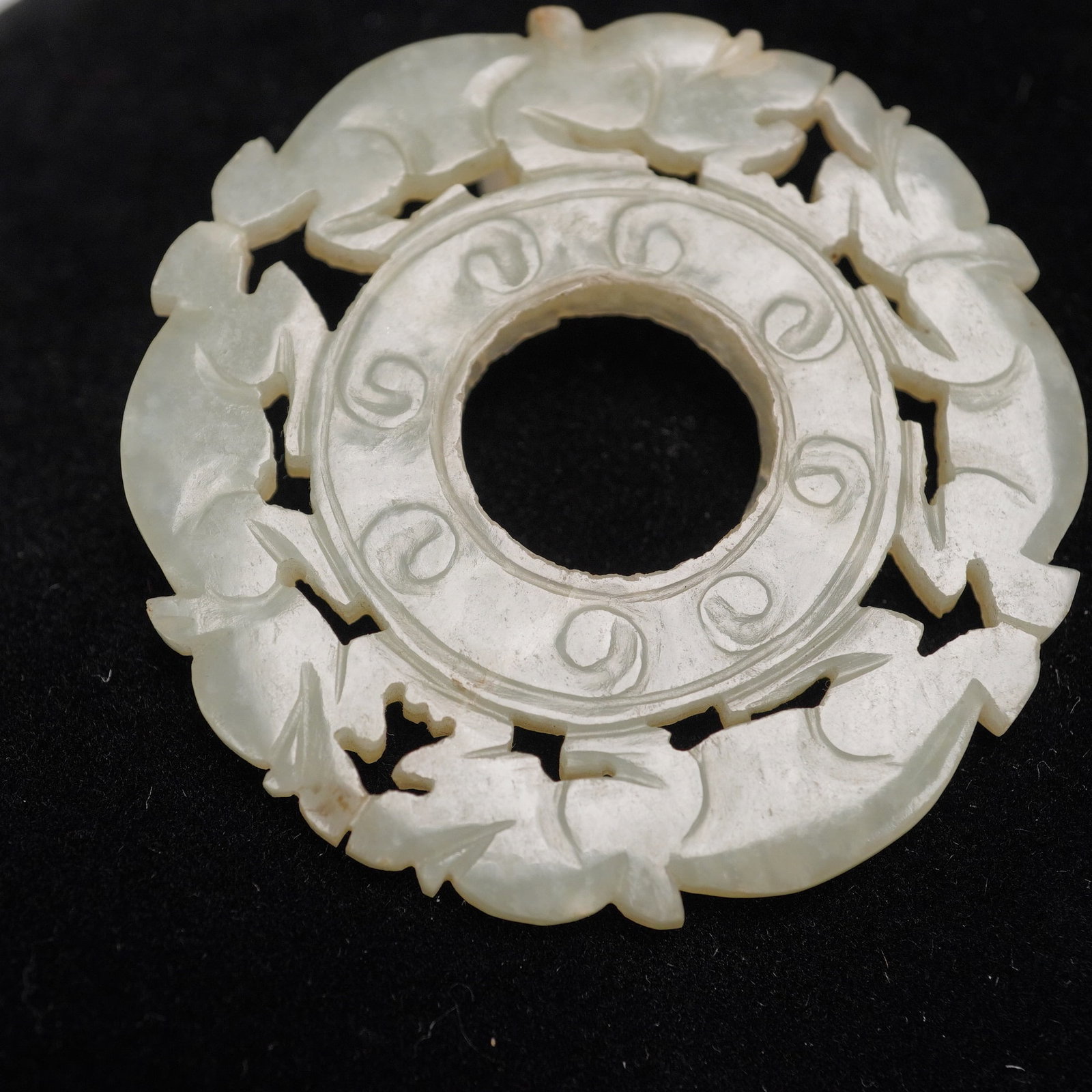 Carved Jade Disc Pendant, Paired Beast Motif: This intricately carved circular jade pendant features a dynamic openwork design of stylized mythical beasts, arranged in symmetrical pairs, face to face and tail to tail, encircling a central apertur
