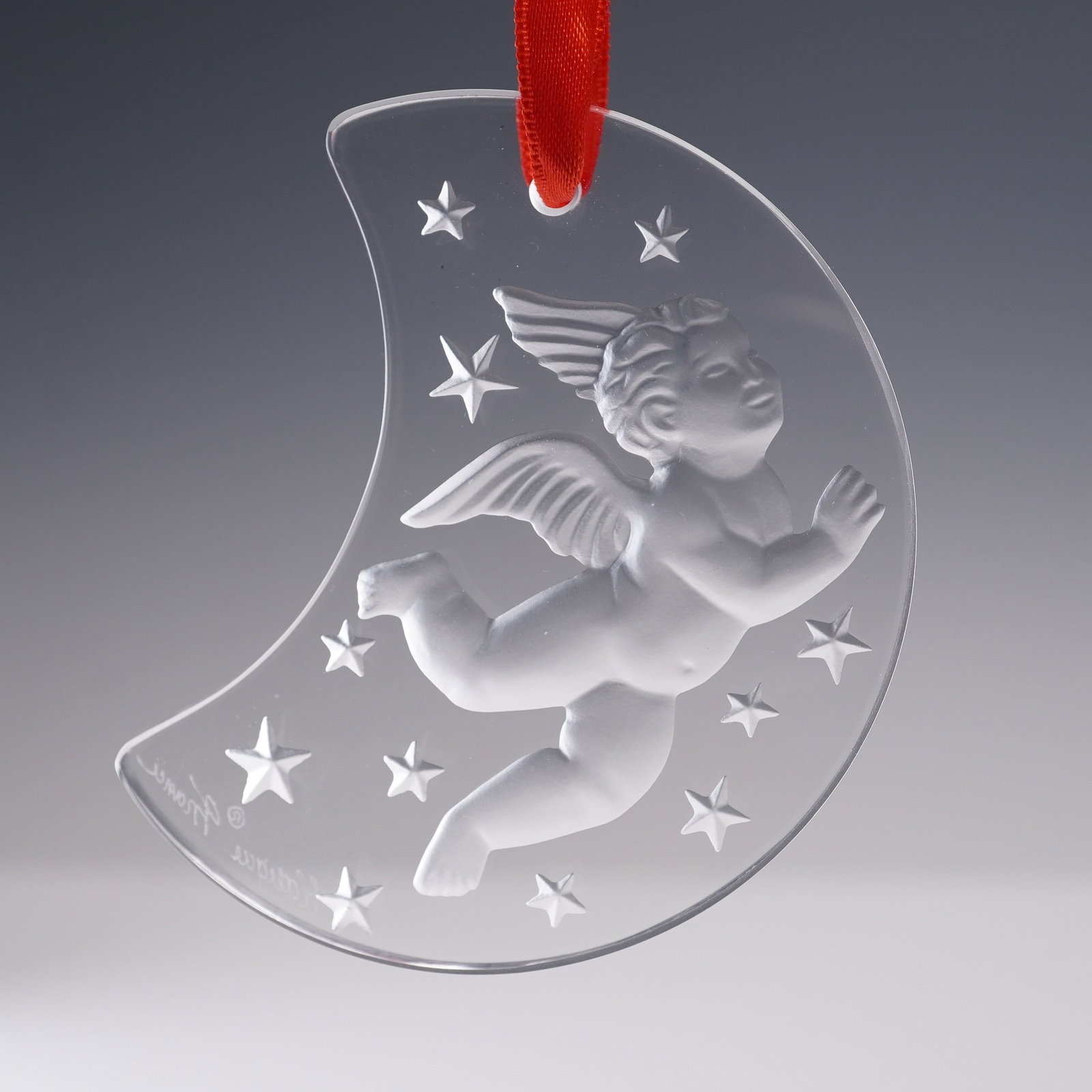 Lalique Crystal Ornament 1998 Christmas Angel: This delicate Lalique crystal ornament features a frosted winged cherub drifting through a crescent moon filled with stars. The design is inscribed Christmas 1998 along the edge and Lalique France nea