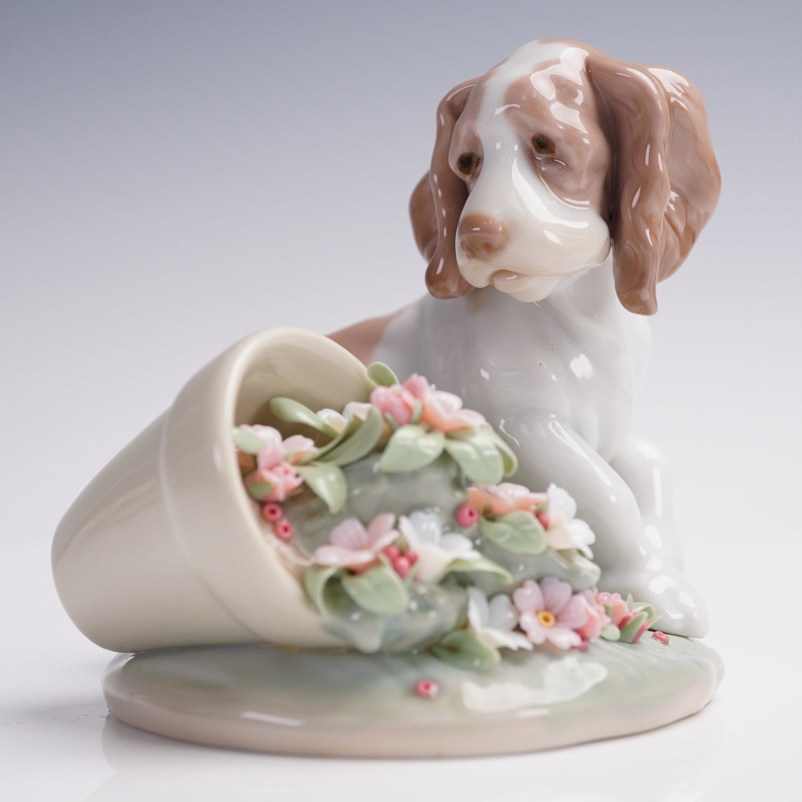 Lladro Porcelain Figurine, It Wasn't Me! 01007672: Charming Lladro porcelain figurine titled It Wasn't Me! model number 7672, depicting a bashful puppy seated beside a spilled flowerpot. Sculpted by Antonio Ramos and issued in 1998 for the Lladro Coll
