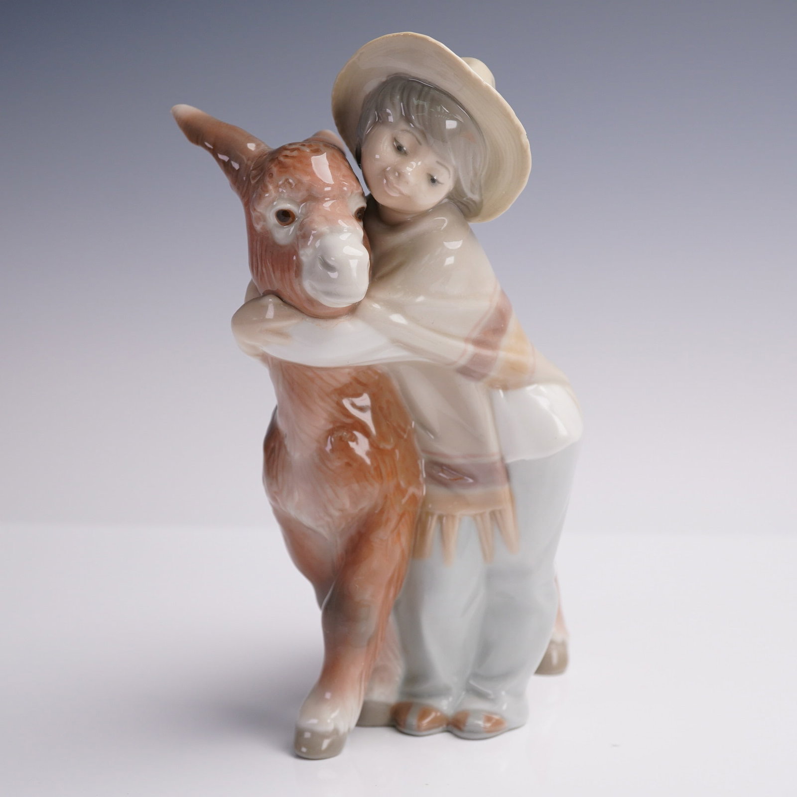 Lladro Porcelain Figurine, Platero and Marcelino, 1181: This charming Lladro porcelain figurine titled Platero and Marcelino depicts a tender moment between a young boy and his faithful donkey, inspired by the classic Spanish tale Platero y yo by Juan Ramo