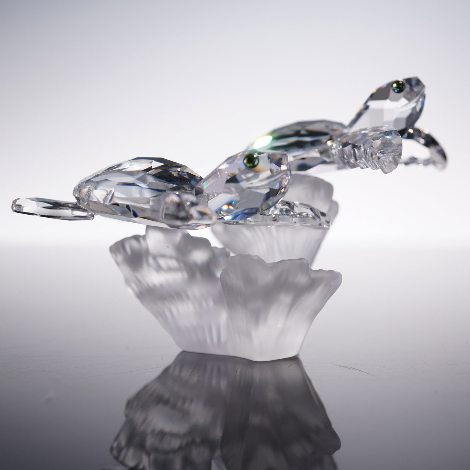 Swarovski Crystal Figurine, Baby Sea Turtles: Faceted clear crystal baby sea turtles glide above coral in this striking Swarovski figurine designed by Michael Stamey. Featuring two turtles in mid-swim, each with iridescent eyes, the piece rests o