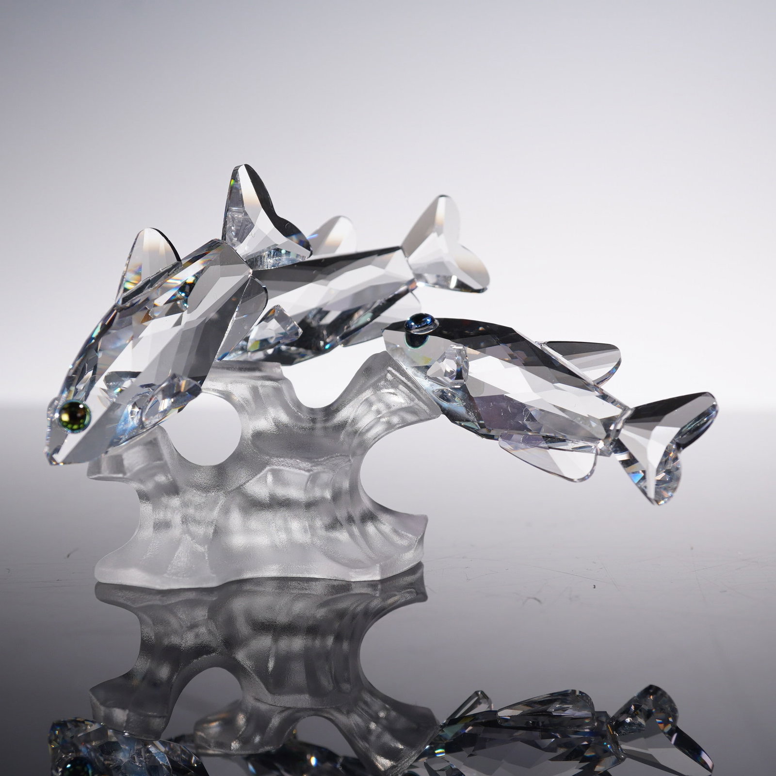 Swarovski Crystal Figurine, South Sea Fish: Swarovski Silver Crystal figurine titled "South Sea Fish," depicting a dynamic school of leaping tropical fish in faceted clear crystal with colored crystal eyes. The group is mounted on a frosted cry