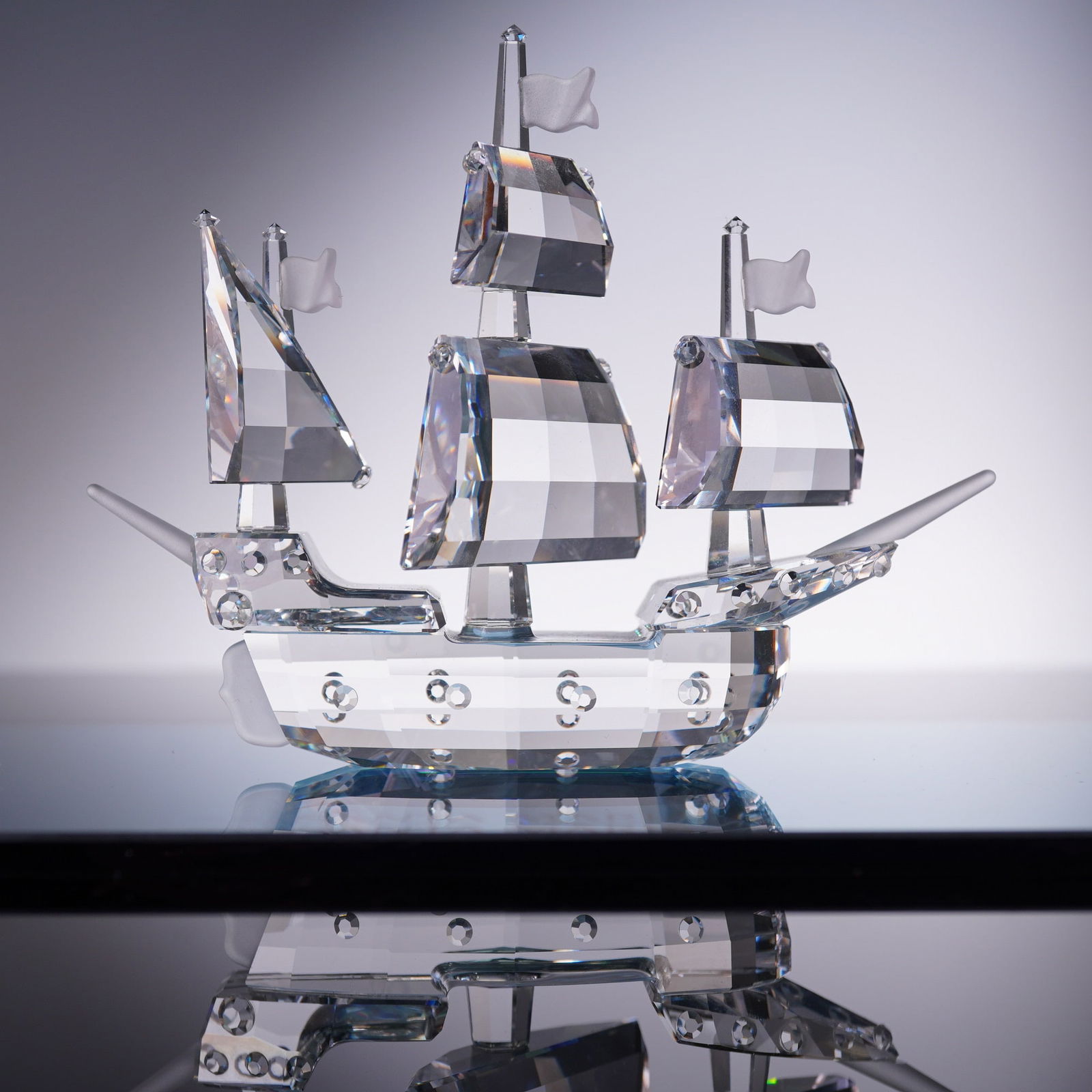 Swarovski Crystal Figurine, Santa Maria: A detailed Swarovski crystal model of the Santa Maria, designed by Gabriele Stamey, model number 162882. Rendered in faceted clear crystal with frosted flag accents, this sailing ship features three m