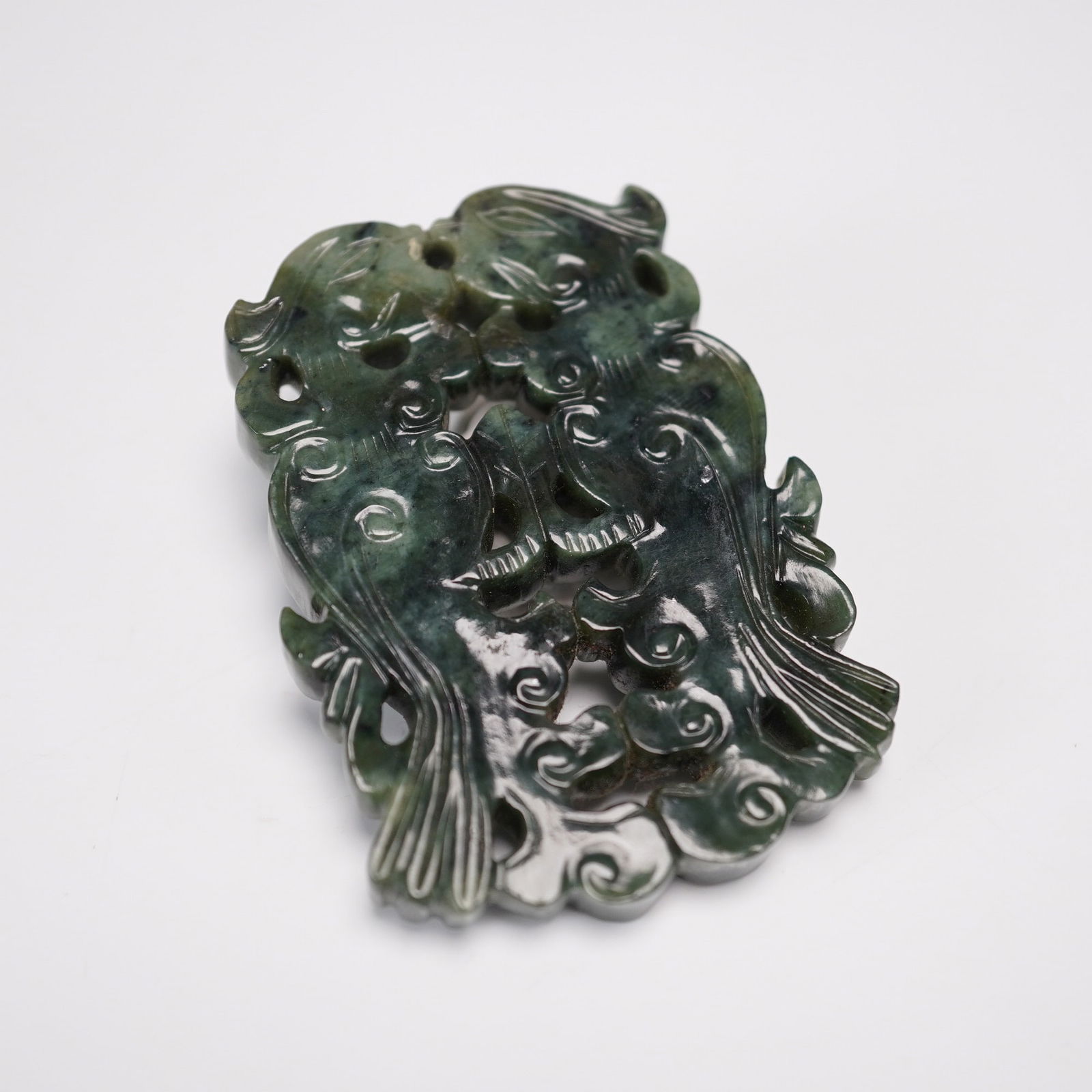 Carved Jade Pendant, Double Phoenix Motif: This finely carved green jade pendant features a mirrored double phoenix design, a powerful emblem of harmony, prosperity, and renewal in traditional Chinese symbolism. The phoenix, revered as a mythi