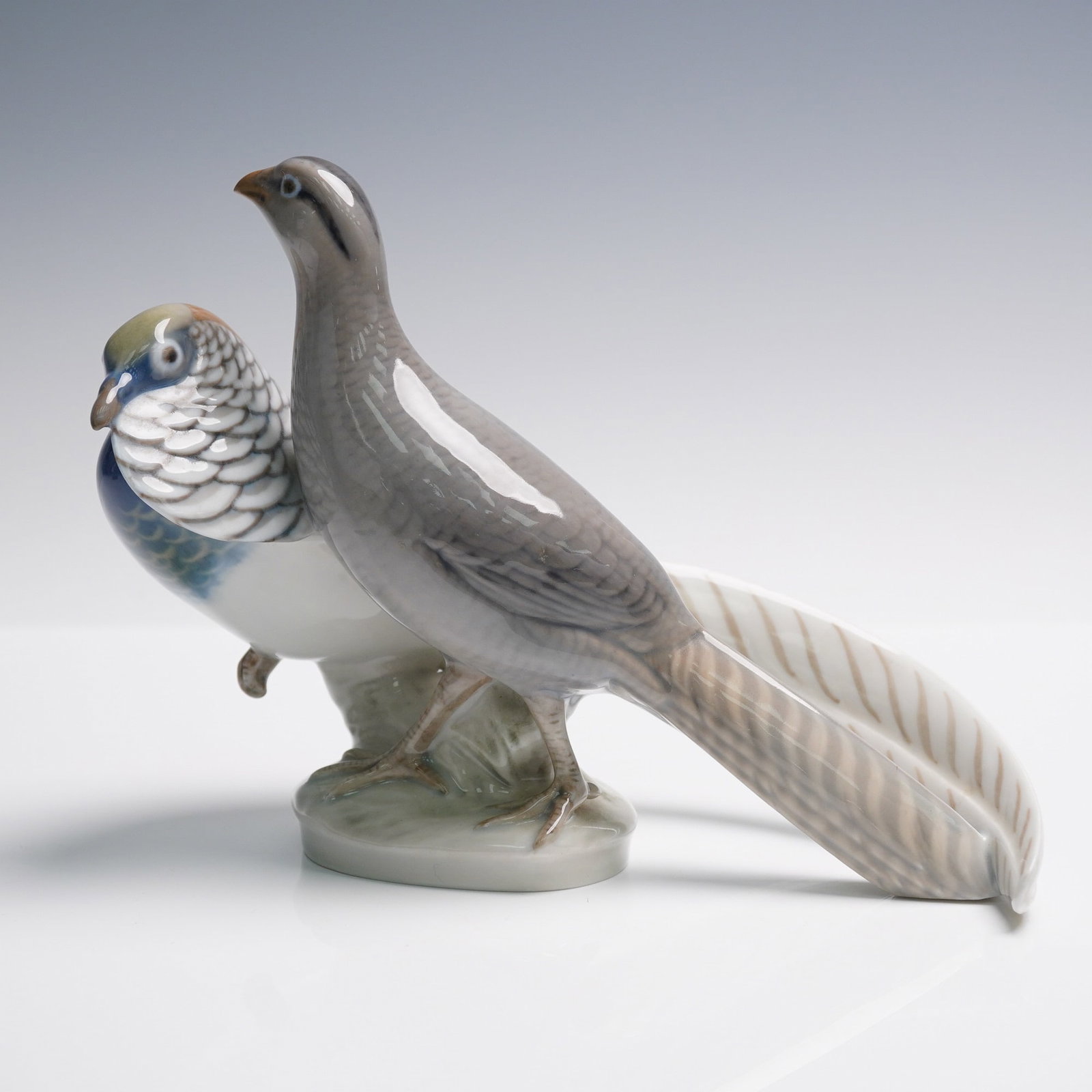 Royal Copenhagen Porcelain Figurine, Pheasants 862: Royal Copenhagen porcelain figurine depicting a pair of pheasants on a naturalistic base, finished in soft gray and blue tones. Marked with Royal Copenhagen Denmark backstamp and model number 862. Iss