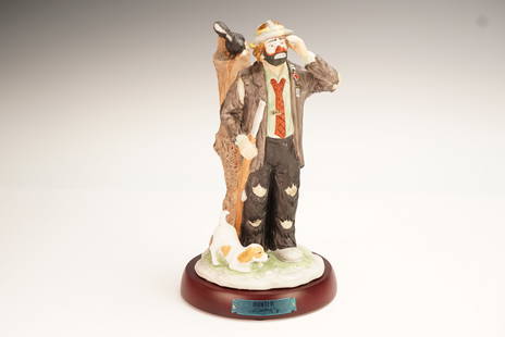 Flambro Emmett Kelly Jr. Figurine, Hunter 9601: This hand-painted porcelain sculpture depicts a whimsical hunter dressed in a patched suit, accompanied by a dog and a skunk perched on a tree stump. The base features a metallic blue nameplate marked