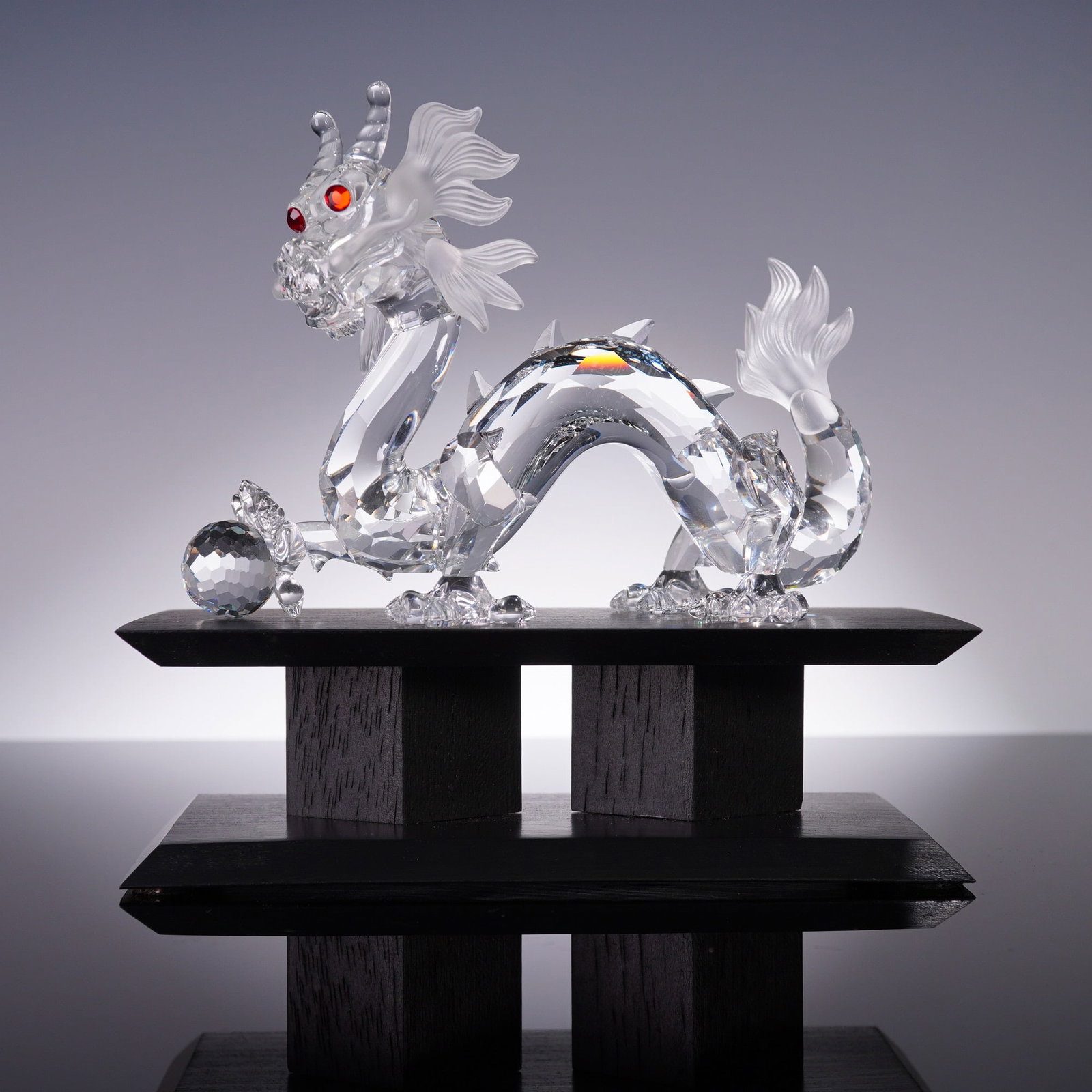 Swarovski Crystal 1997 Annual Edition Figurine, The Dragon with Base: A dazzling Swarovski Crystal Society (SCS) Annual Edition figurine titled The Dragon, designed by Gabriele Stamey and released in 1997. Crafted in faceted clear crystal, this dynamic Eastern-style dra