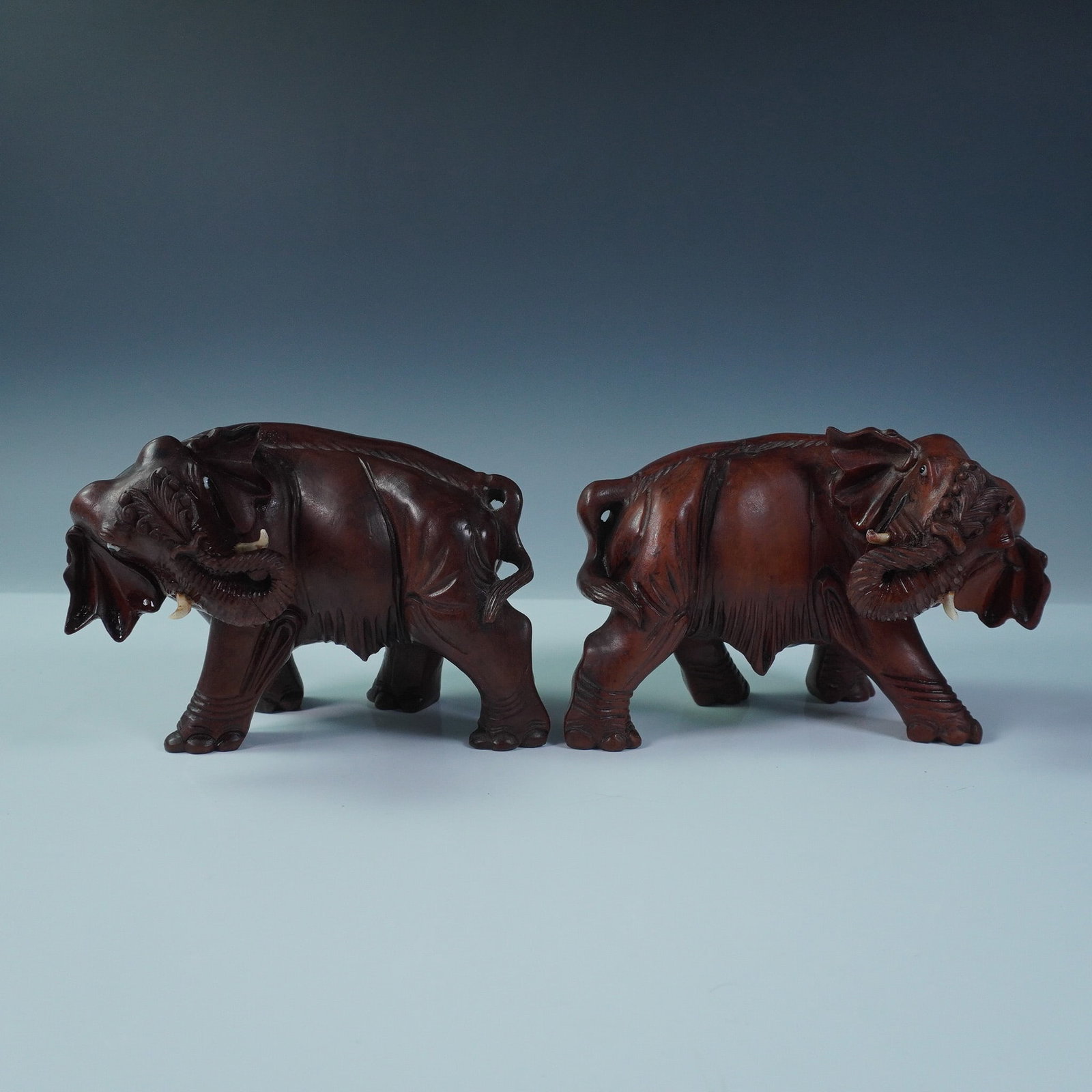 2pc Carved Hardwood Elephant Figurines: A well-crafted pair of carved hardwood elephant figures, each depicted mid-stride with raised trunks and expressive musculature and eyes. Likely produced for the mid-20th century export market, these 