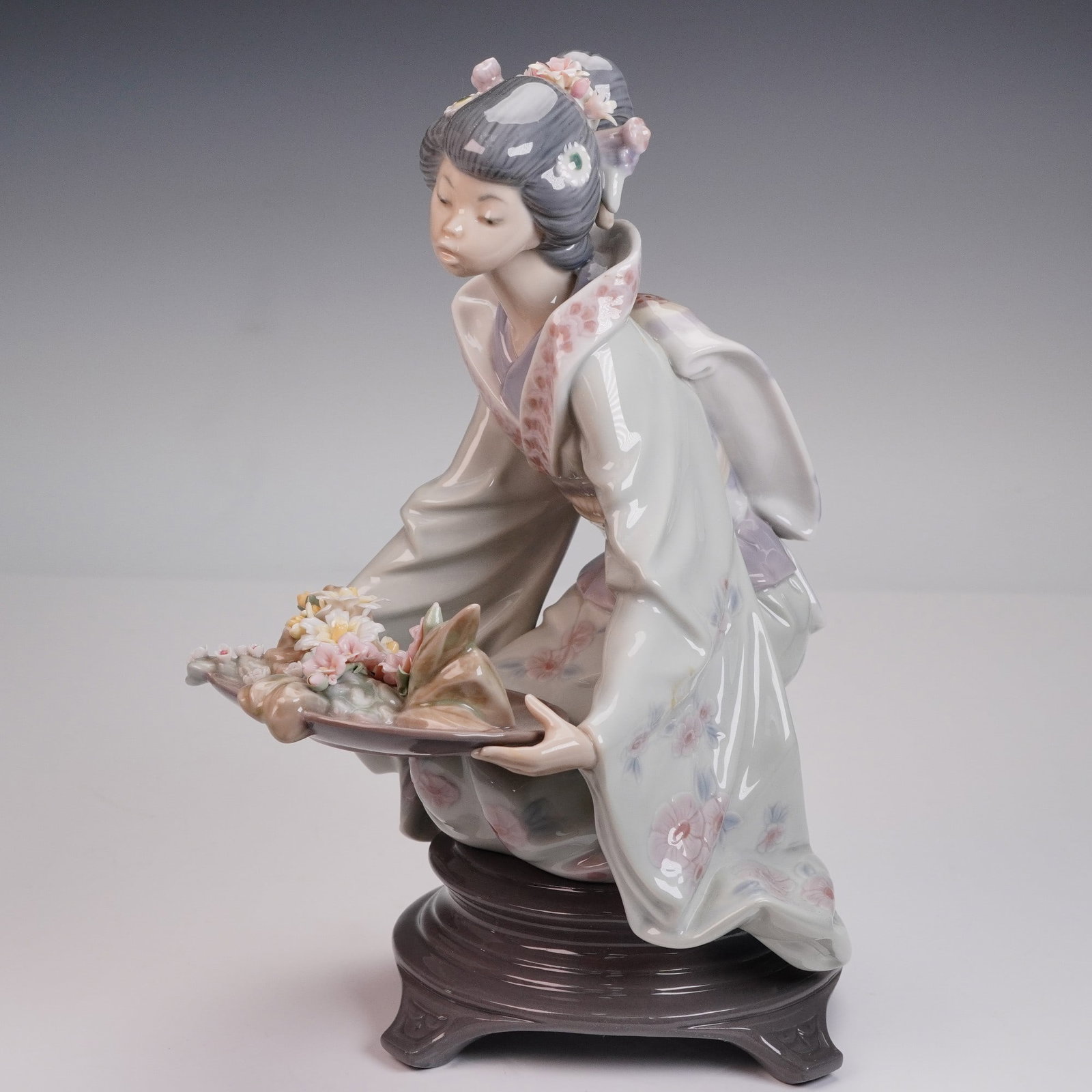 Lladro Porcelain Figurine Gift of Beauty 01005775 Boxed: Lladro porcelain figurine titled Gift of Beauty, item number 01005775, depicting a kneeling geisha holding a floral arrangement on a tray. Features a glossy finish with detailed hand-painted pastel to