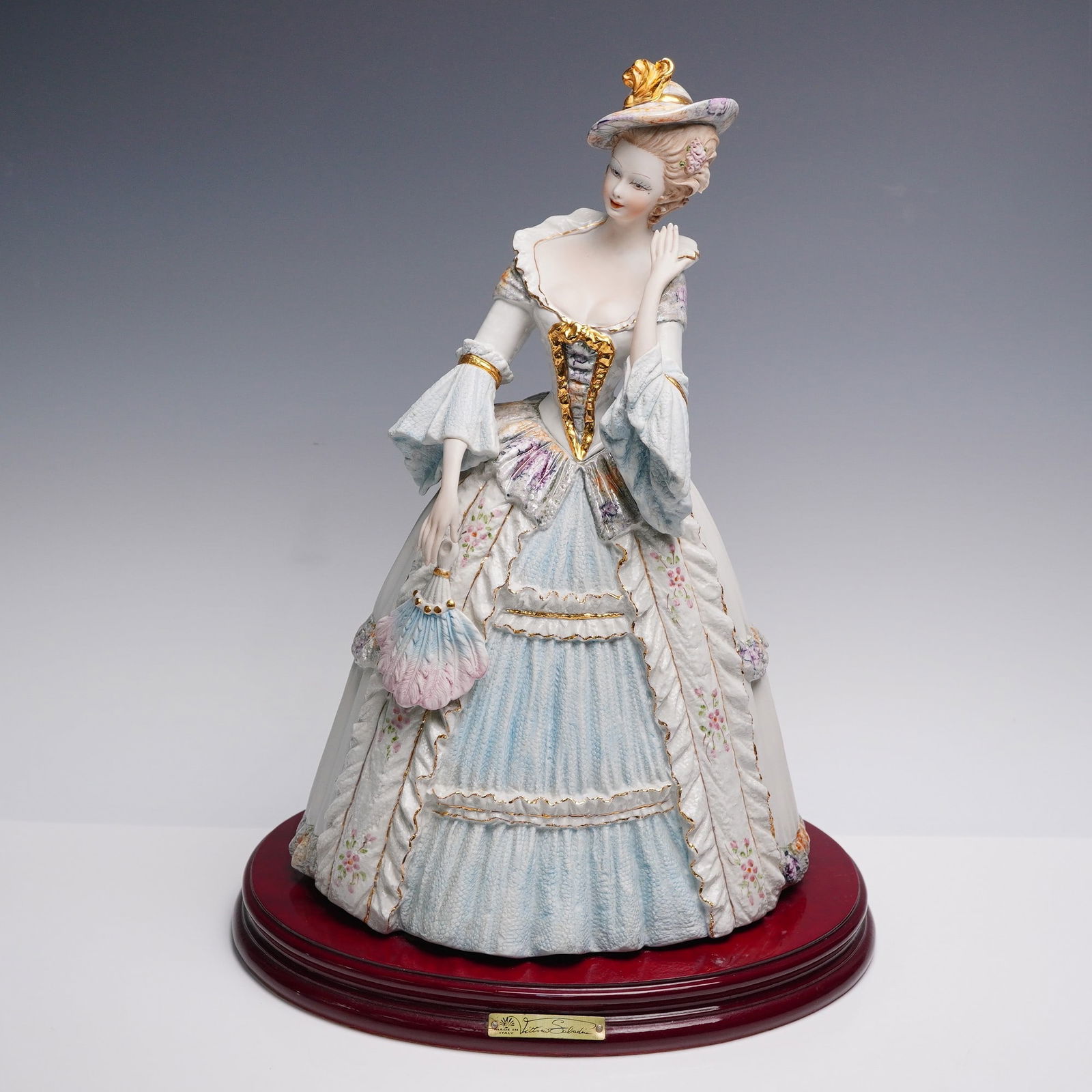 Vittorio Sabadin Capodimonte Elegant Fan Lady Porcelain Figurine: Captivating porcelain figurine by Vittorio Sabadin for Capodimonte, made in Italy, showing an elegant lady in a flowing pale blue and white gown adorned with delicate floral accents and shimmering gol