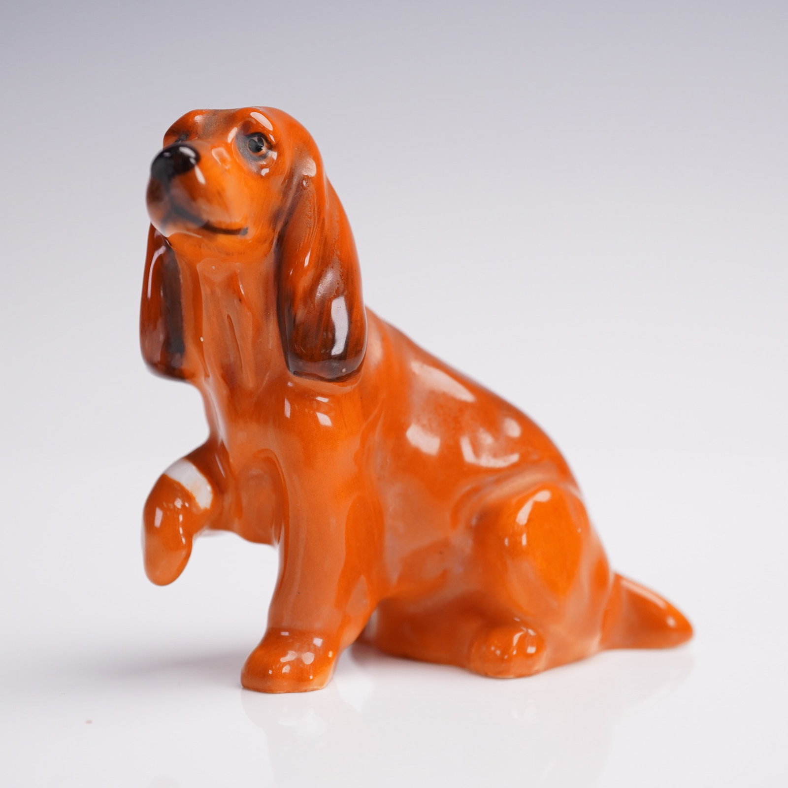 Royal Doulton Figurine, Cocker Spaniel, K9: Offered here is a charming and collectible Royal Doulton bone china figurine depicting a seated spaniel-type dog with one paw raised, often referred to as the "K9" model. Finished in a vibrant orange 