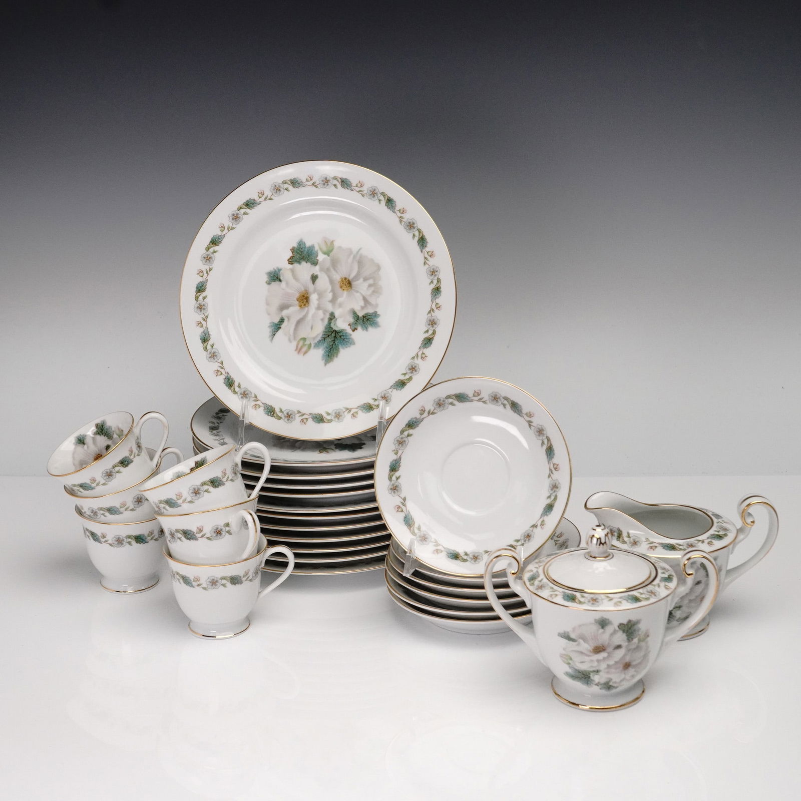 26pc Noritake Porcelain Dinnerware Set, Magnolia Pattern: This refined 26-piece Noritake porcelain dinnerware set features the beloved Magnolia pattern, showcasing large white magnolia blooms with green foliage at the center of each plate, encircled by a flo