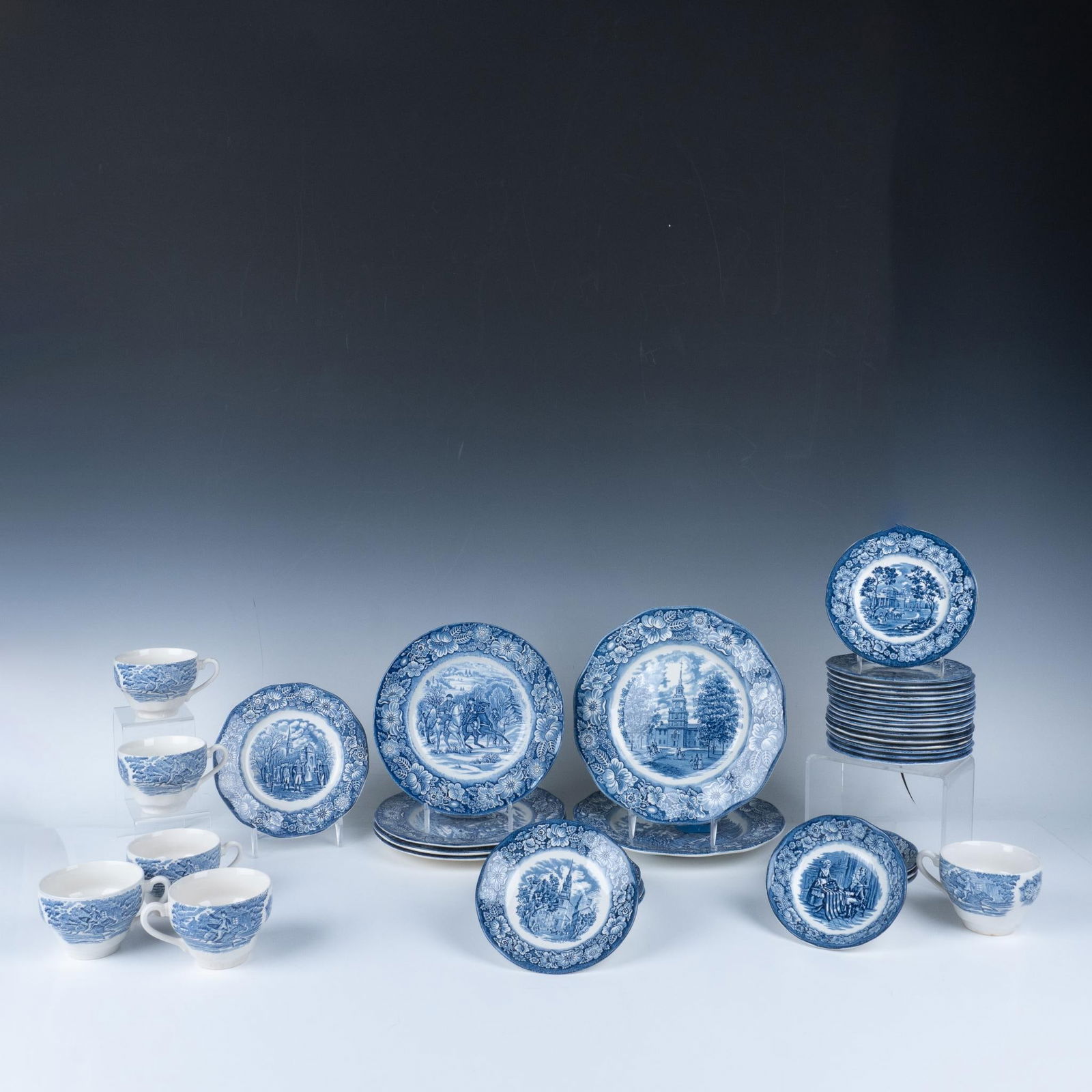 39pc Vintage Liberty Blue Ironstone Dinnerware: Lovely blue design over white of historic scenes in center with floral rims. Lot includes 2 dinner plates (10"); 4 salad plates (9"); 1 side plate (7"); 17 bread plates (6"); 4 fruit bowls (5"); 5 sau