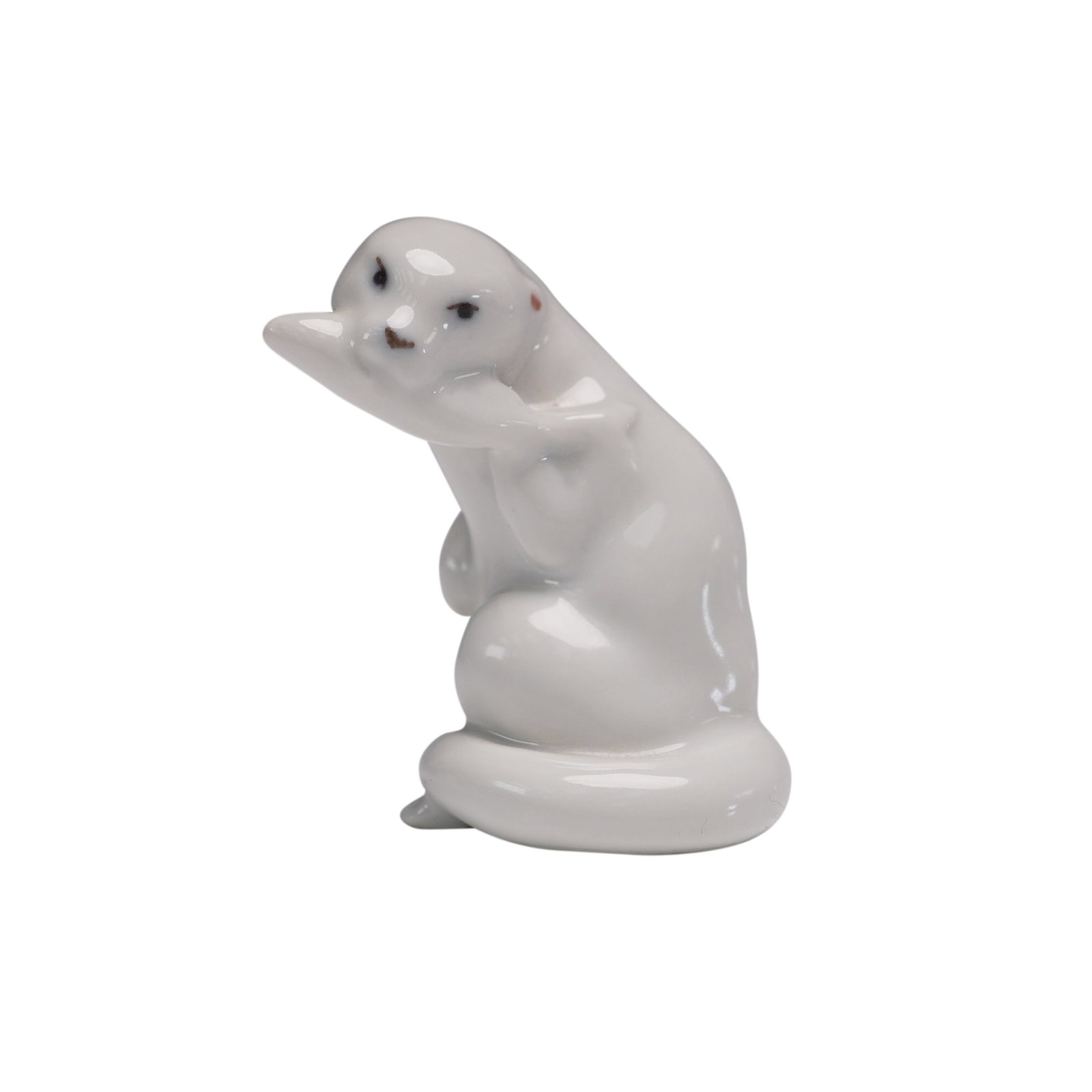 Royal Copenhagen White Otter Figurine No. 2233: This elegant Royal Copenhagen porcelain figurine depicts an otter in a seated pose, capturing a graceful moment in nature. The figurine is entirely finished in a smooth white glaze, enhancing its mini