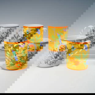 4pc Hermes La Siesta Porcelain Mugs: Set of four porcelain mugs by Hermes in the La Siesta pattern. Each features a vibrant tropical design with birds, butterflies, and fruit against a bright yellow background, trimmed in orange. Marked