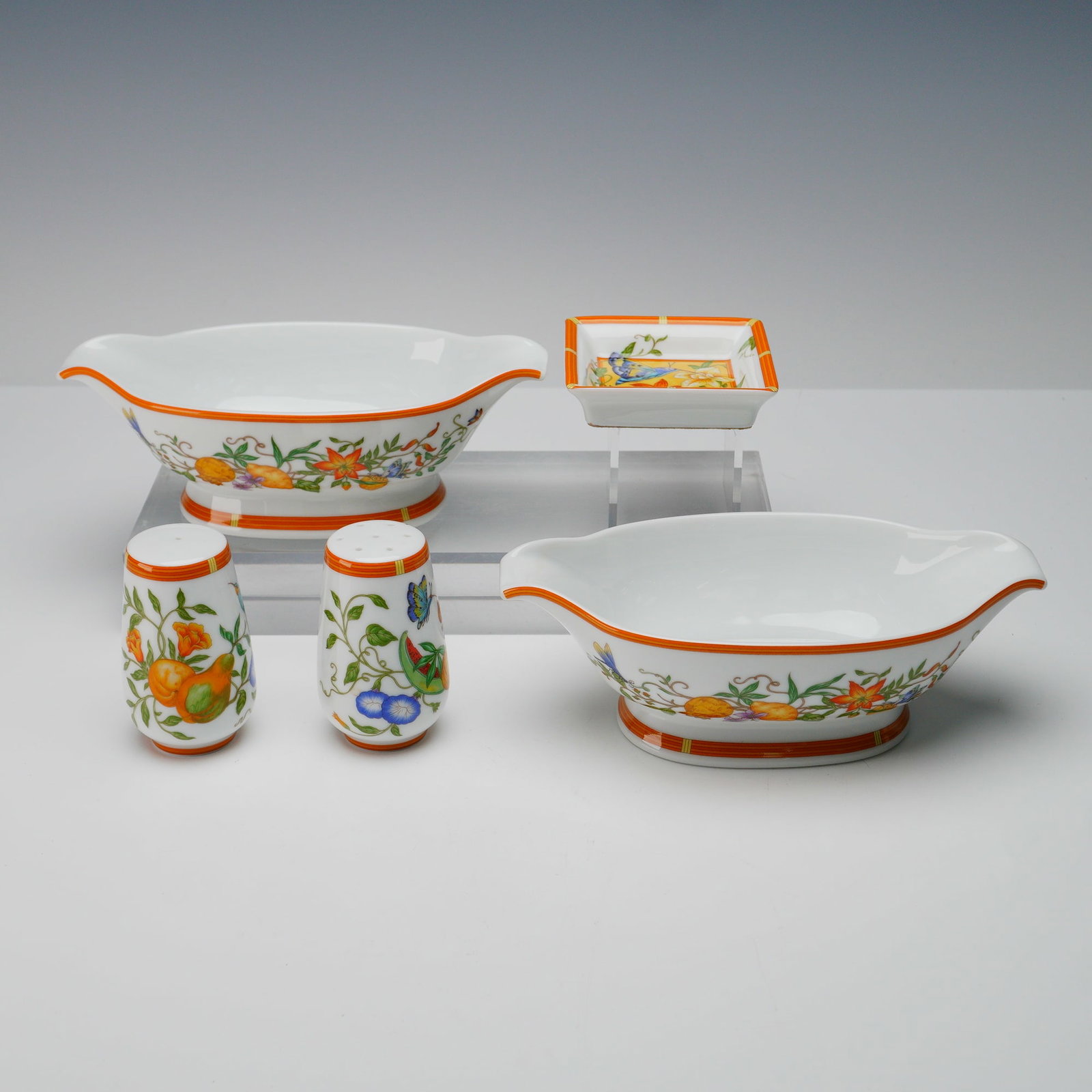 5pc Hermes La Siesta Porcelain Serveware Set: Five-piece porcelain serveware set by Hermes in the La Siesta pattern. Includes two gravy boats 7.5"L, salt and pepper shakers 3.25"H, and one square dish 3.25"L. Decorated with vibrant florals, butte