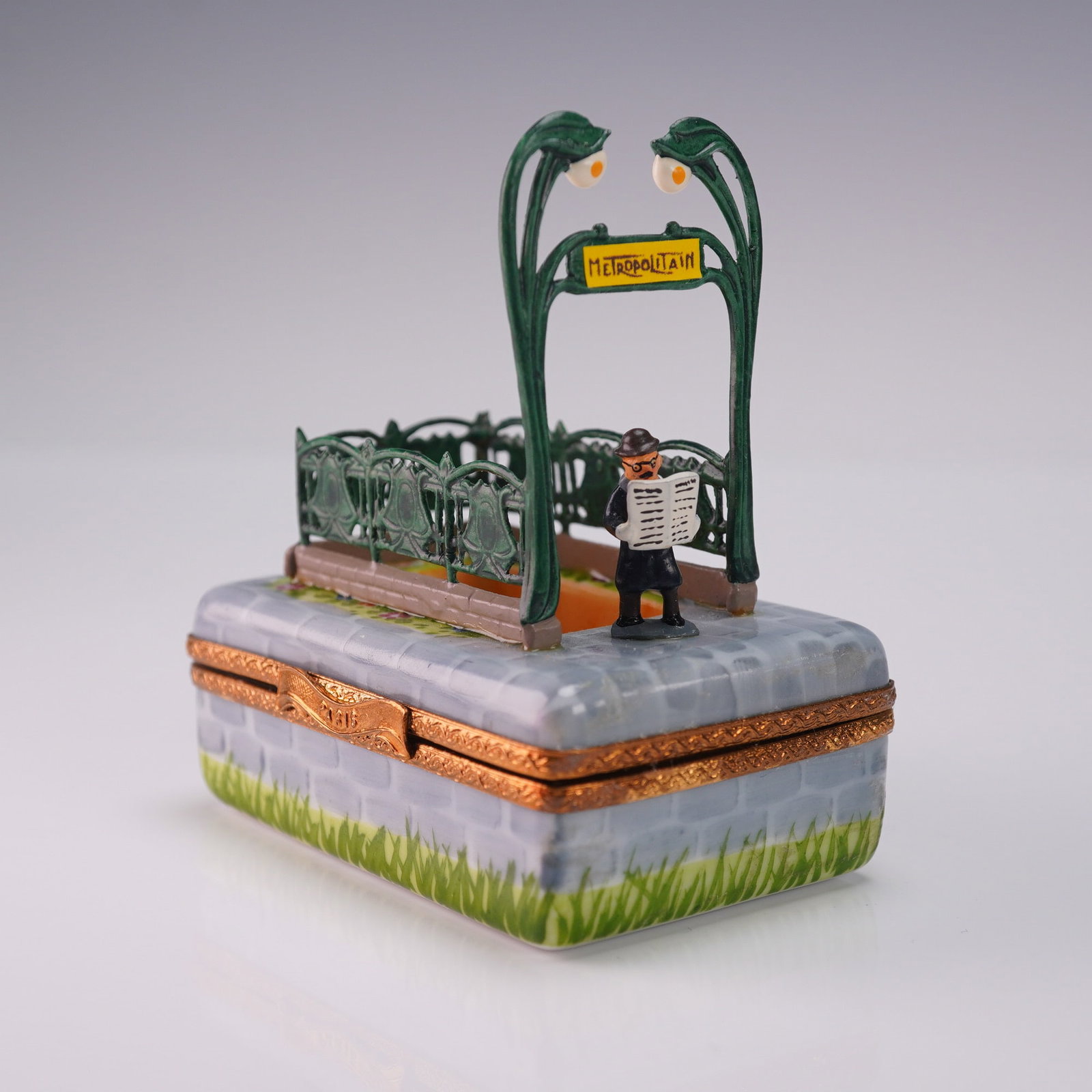 Limoges Porcelain Box Paris Metro Scene: Hand painted Limoges porcelain box depicting a Paris Metro entrance with Art Nouveau railings, twin streetlamps, and a figure reading a newspaper. The interior features a painted underground train sce