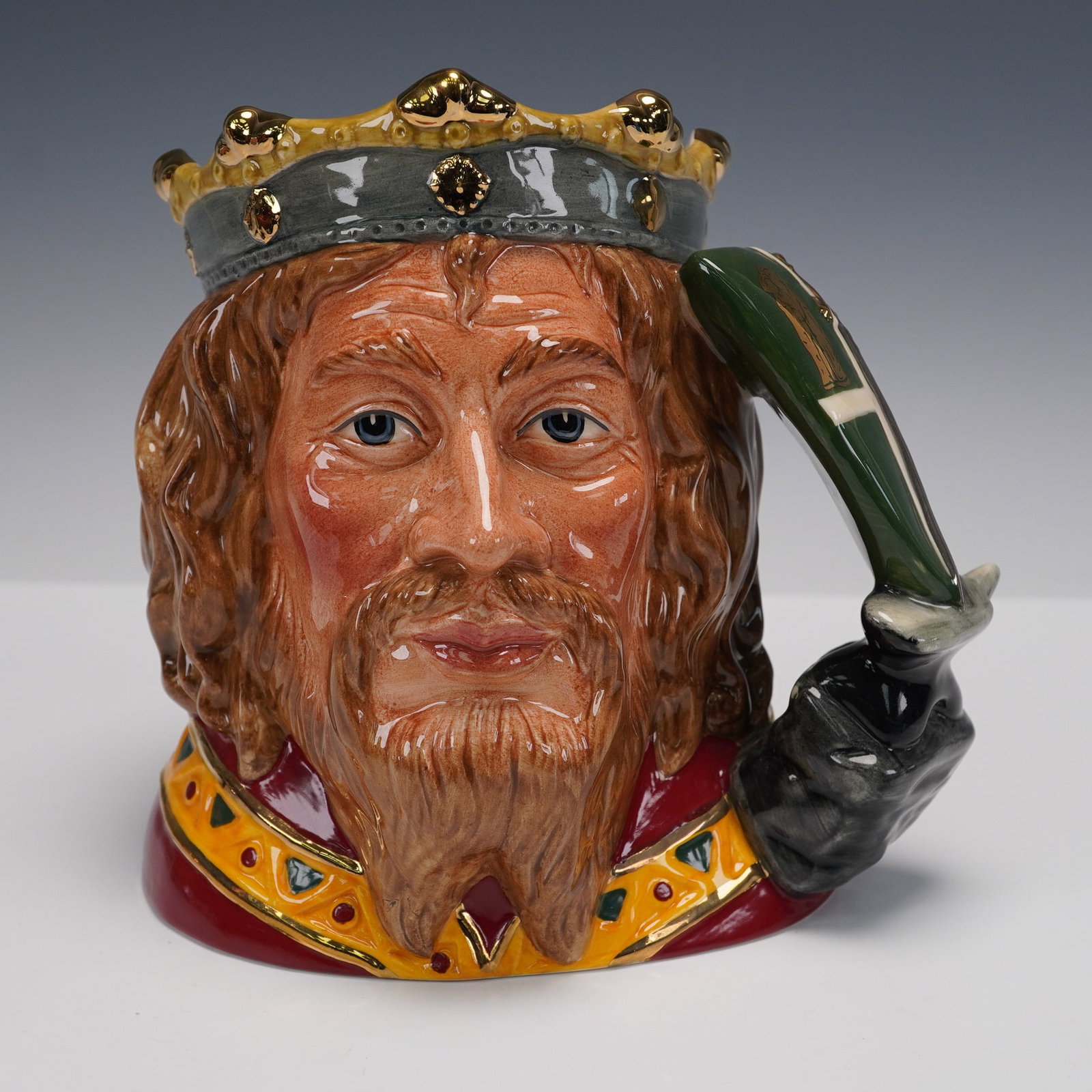 Royal Doulton Character Jug King Arthur D7055: This Royal Doulton King Arthur character jug (D7055) features an intricately detailed portrait of the legendary king, complete with a golden crown and a distinctive quill. The jug is hand-painted with